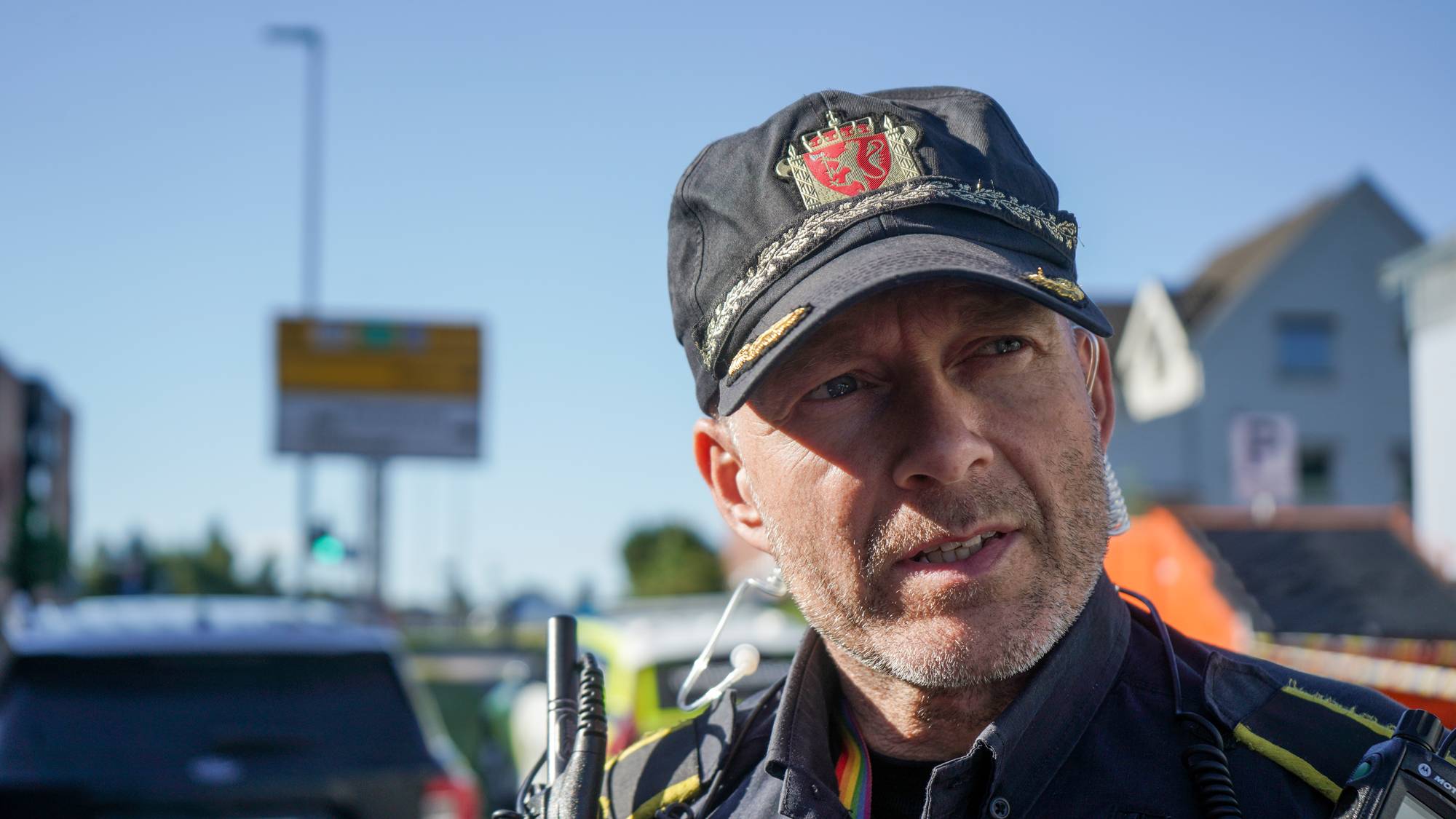 Politibetjent med uniform og caps snakker utendørs ved en vei. (Bildebeskrivelsen er laget av en KI-tjeneste)