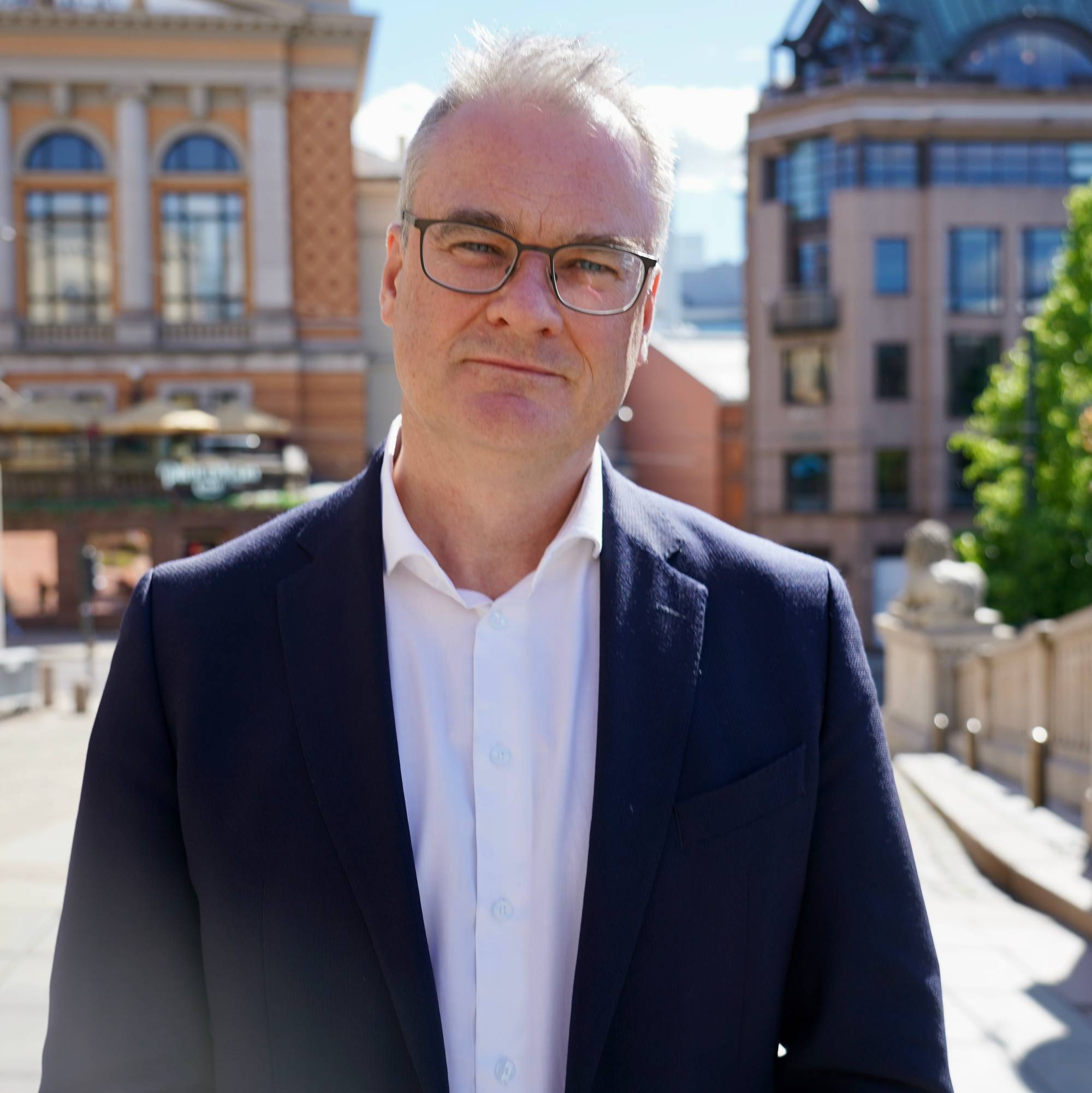 Mann i dress og skjorte utendørs i Oslo sentrum. (Bildebeskrivelsen er laget av en KI-tjeneste)