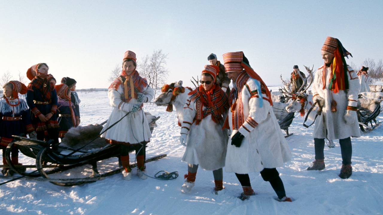 Sonja og Harald i pesk. Finnmarksvidda. April 1969 Kronprinsparet besøker Finnmark. Her kronprins Harald og kronprinsesse Sonja i pesk (midt i bildet) klar til en tur med reinsdyr under besøket på Finnmarksvidda.