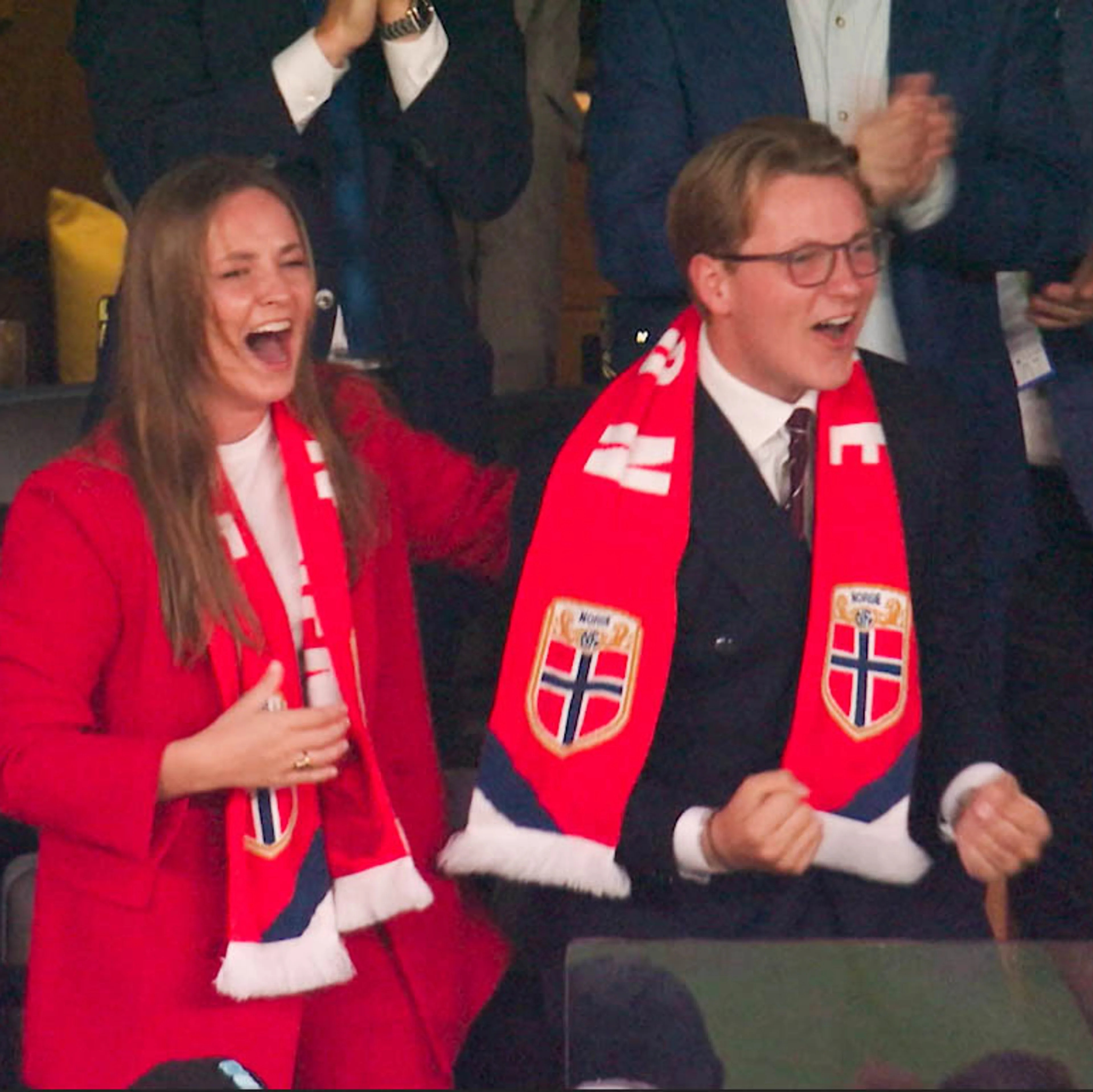 en ung kvinne og en ung mann i pene klær jubler og heier på en tilskuerbenk