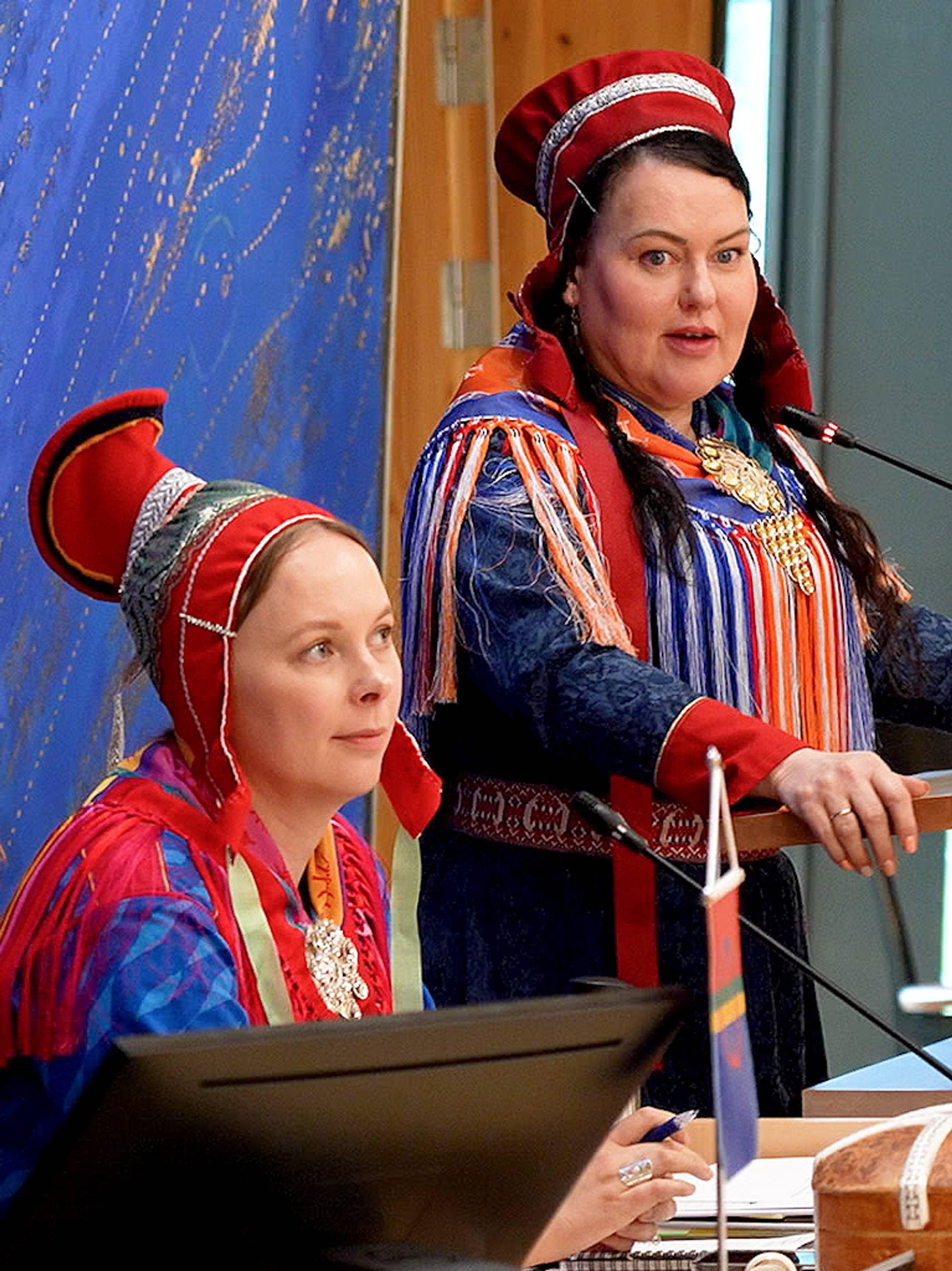 Kvinnelig møteleder med en kvinne ved siden av seg på talerstolen