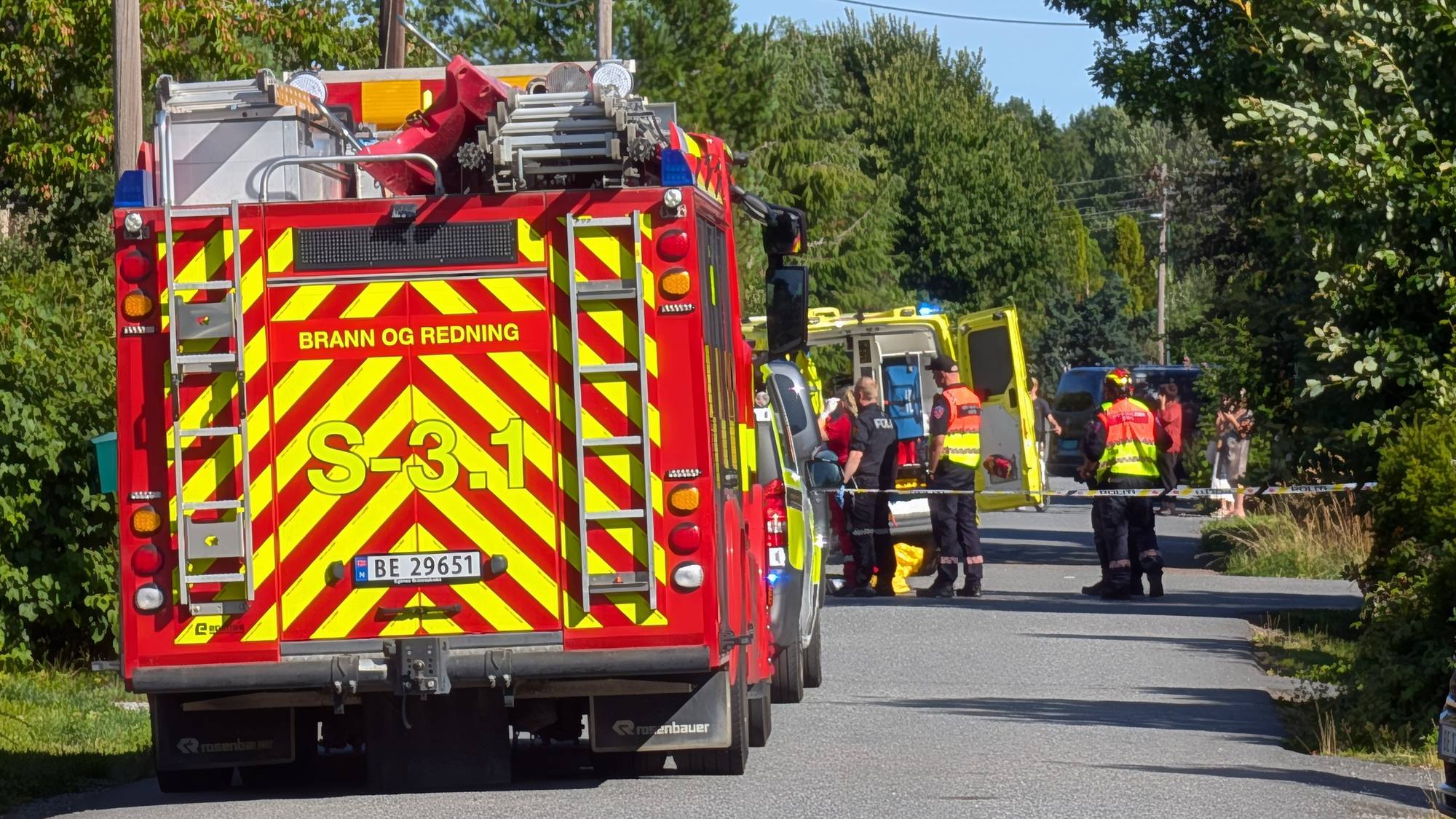 Brannvesen og ambulansepersonell på et ulykkessted i en boliggate med politisperringer. (Bildebeskrivelsen er laget av en KI-tjeneste)
