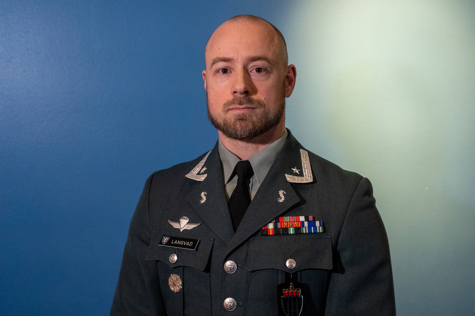 Offiser med navn Langvad i uniform med medaljer foran en blå bakgrunn. (Bildebeskrivelsen er laget av en KI-tjeneste)