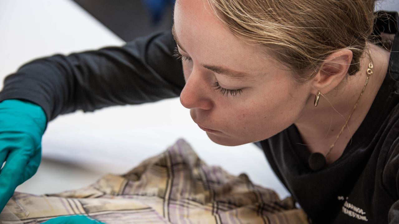 Tekstilkonservator Signe Thøgersen jobber konsentrert med Ørnerovetkjolen.