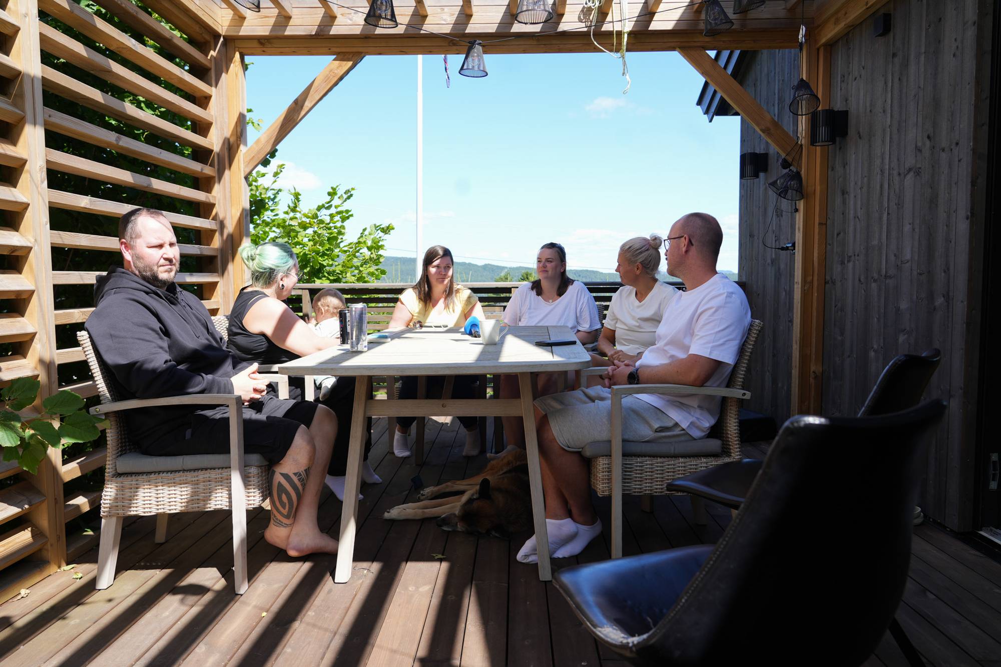 En gruppe mennesker som sitter ute rundt et bord. 