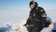 Jon Aars / Norsk Polarinstitutt En person i vinterklær kneler ved siden av en død isbjørn i snøen. Bakgrunnen viser en vidåpen polarregion med is og snø. Personen ser ut til å utføre en oppgave knyttet til dyret. Det er klart sollys, og omgivelsene er stille og øde. (Bildebeskrivelsen er laget av en KI-tjeneste)