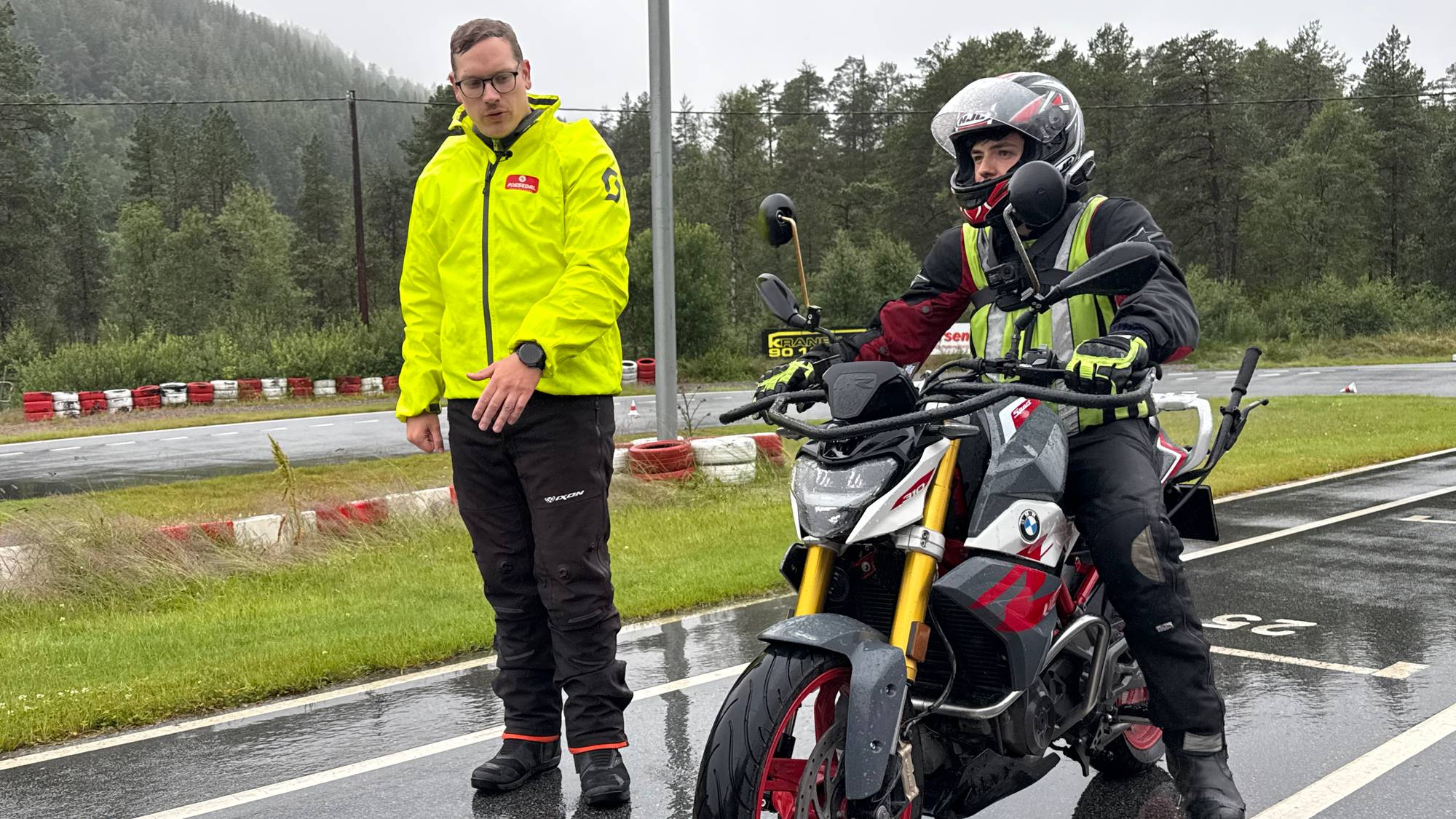 mann i gul jakke instruerar mc-syklist 