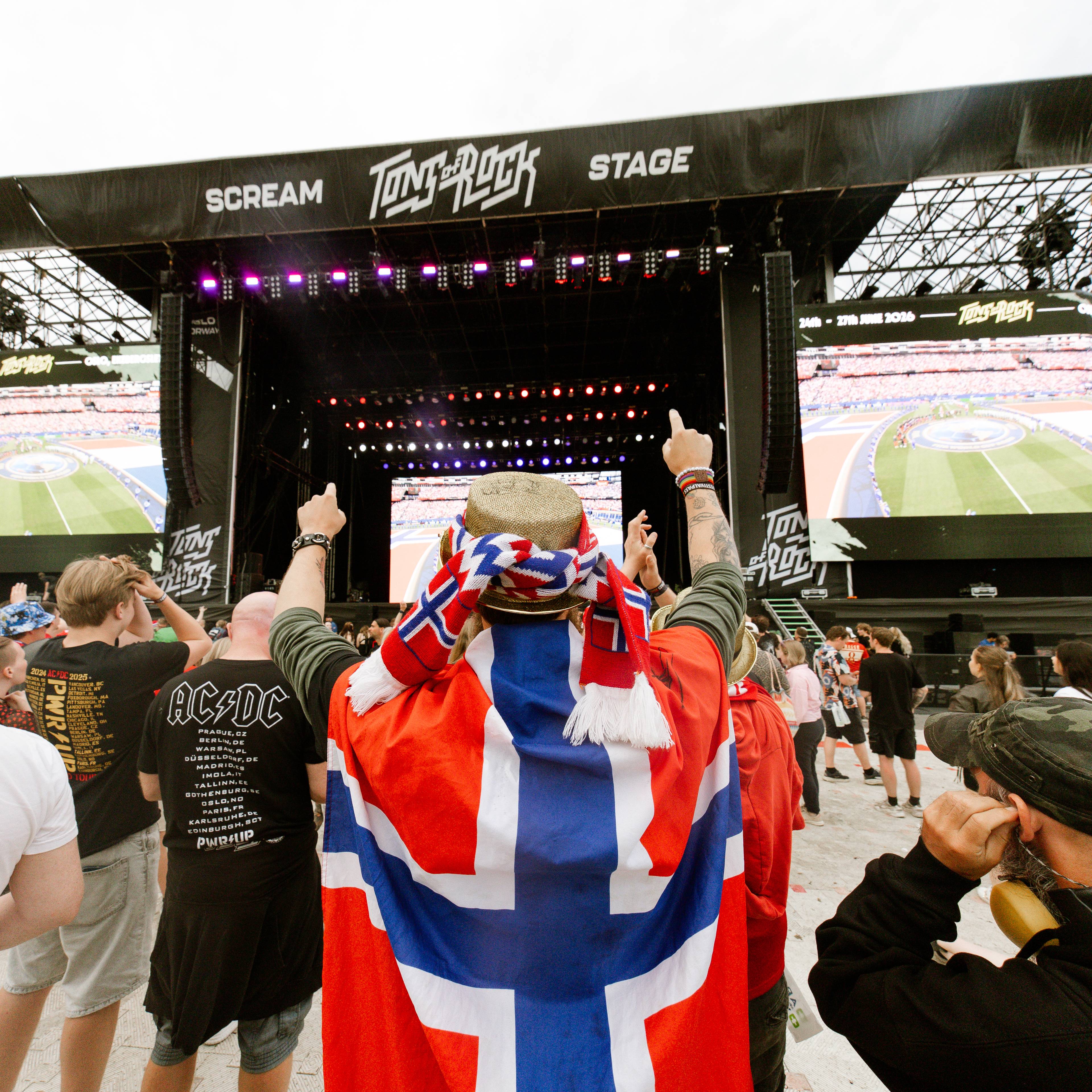 Publikum ser fotballkamp på storskjerm foran en scene under Tons of Rock-festivalen. (Bildebeskrivelsen er laget av en KI-tjeneste)