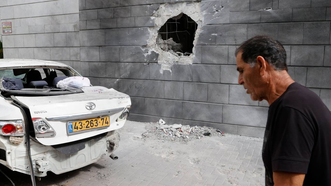 En mann passerer et hull etter en rakett fra Gazastripen traff en mur i byen Ashkelon fredag 14. mai.