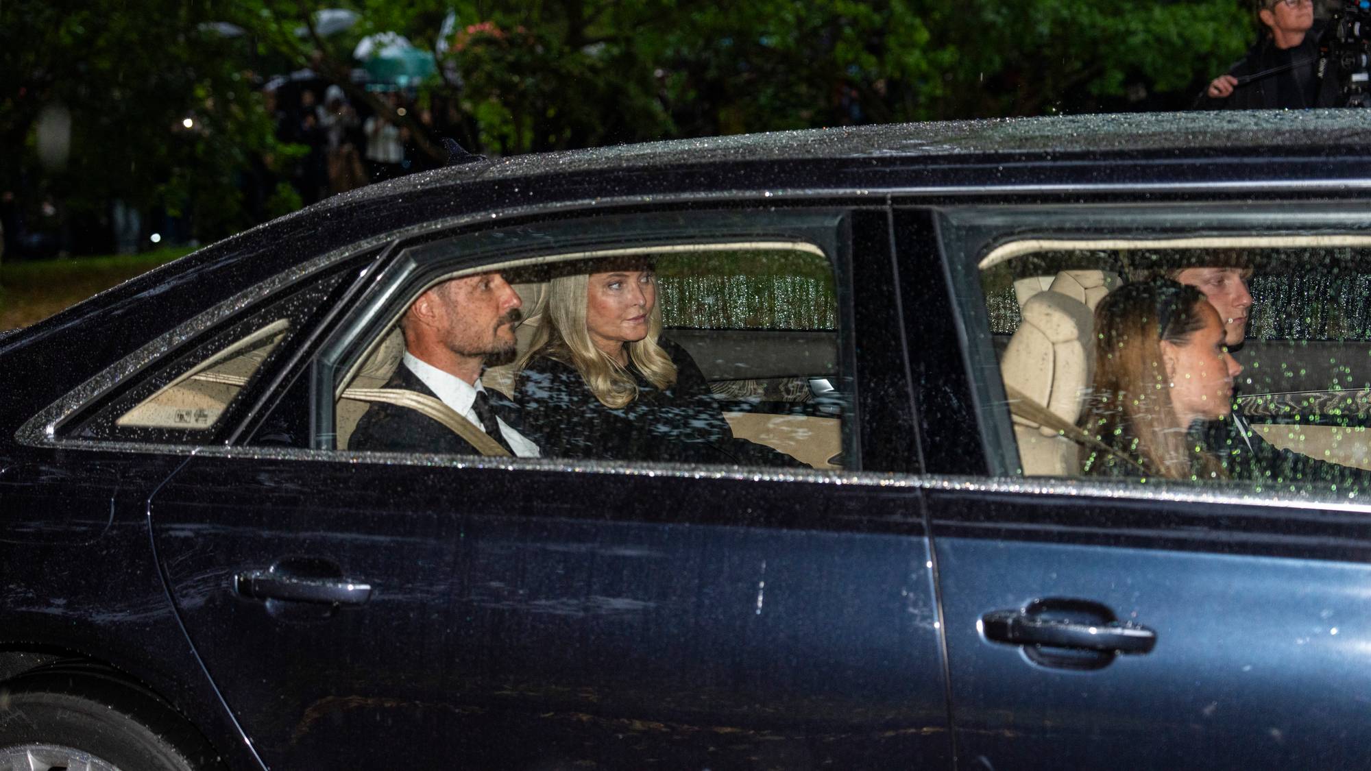 Kong Haakon og dronning Mette-Marit sitter bak i limousinen, foran dem sitter kronprinsesse Ingrid Alexandra og prins Sverre Magnus