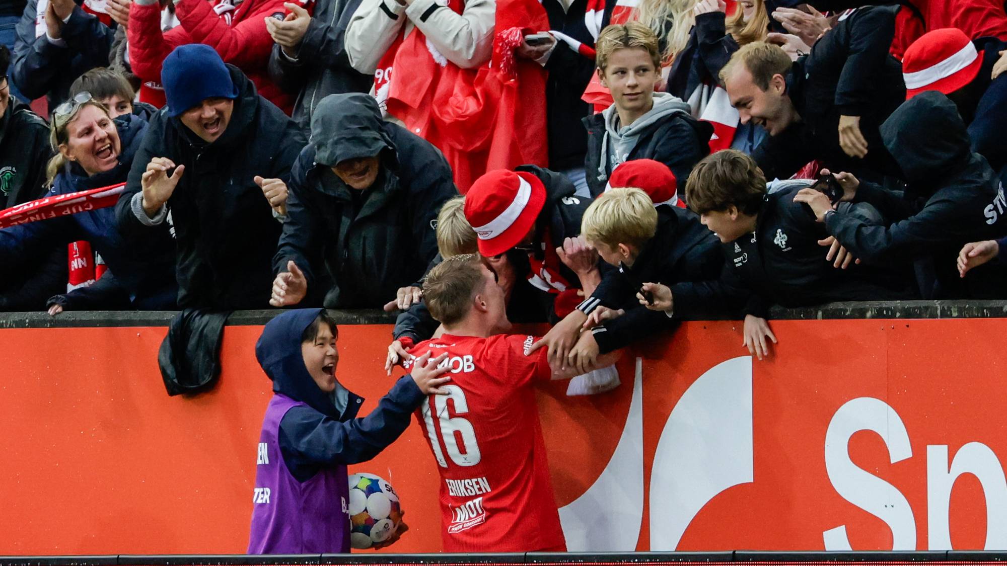 Fotballspilleren Eriksen feirer mål sammen med publikum ved sidelinjen på en stadion. (Bildebeskrivelsen er laget av en KI-tjeneste)
