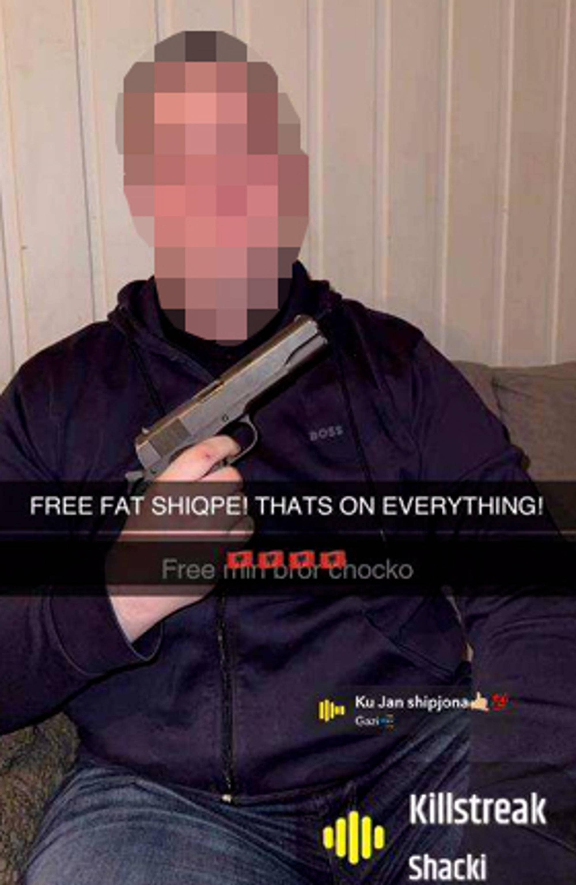 En mann som poserer med en pistol. Mannen sitter i en sofa. Ansiktet hans er sladdet.