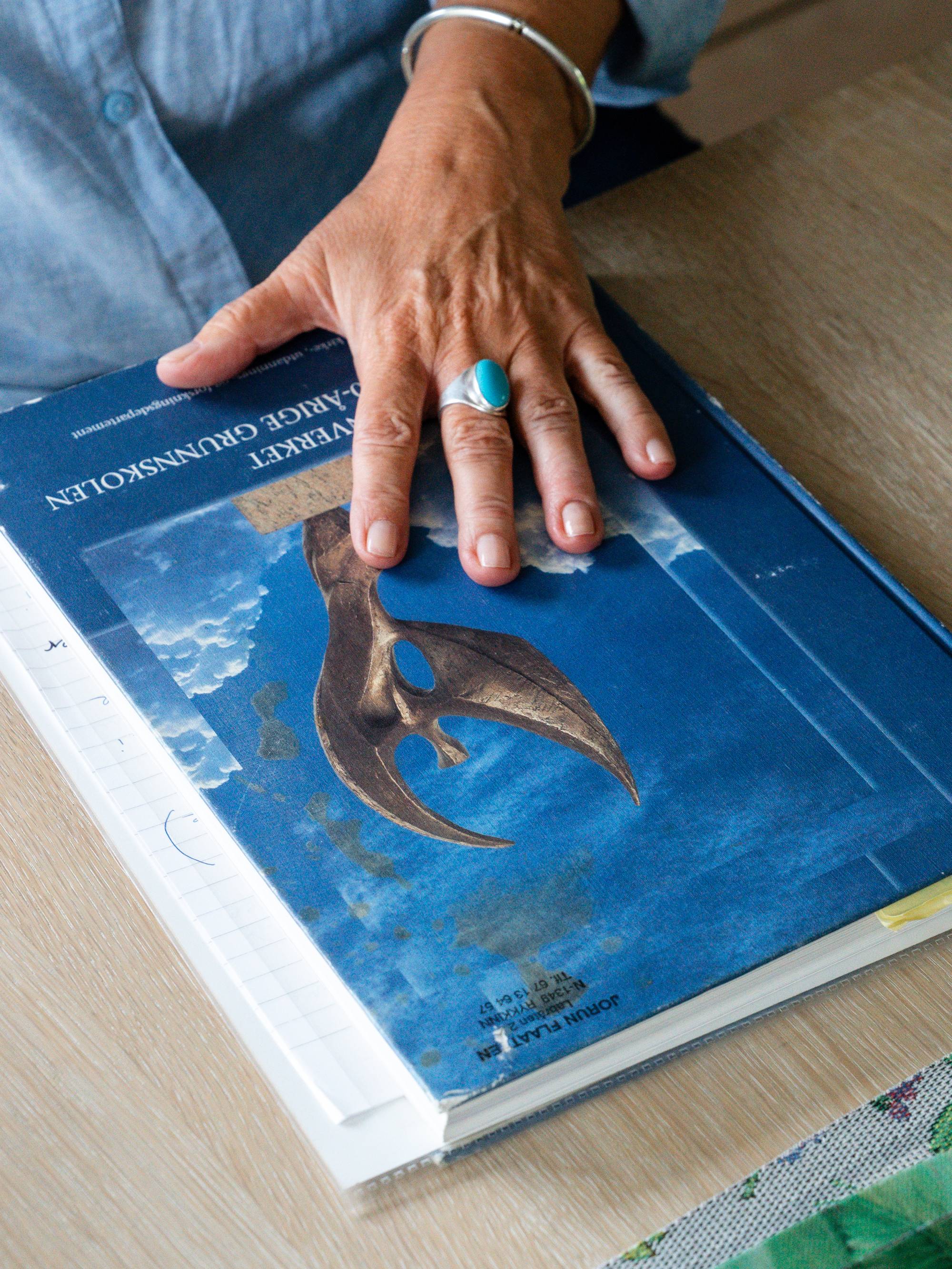 En person holder hånden på en blå bok. (Bildebeskrivelsen er laget av en KI-tjeneste)