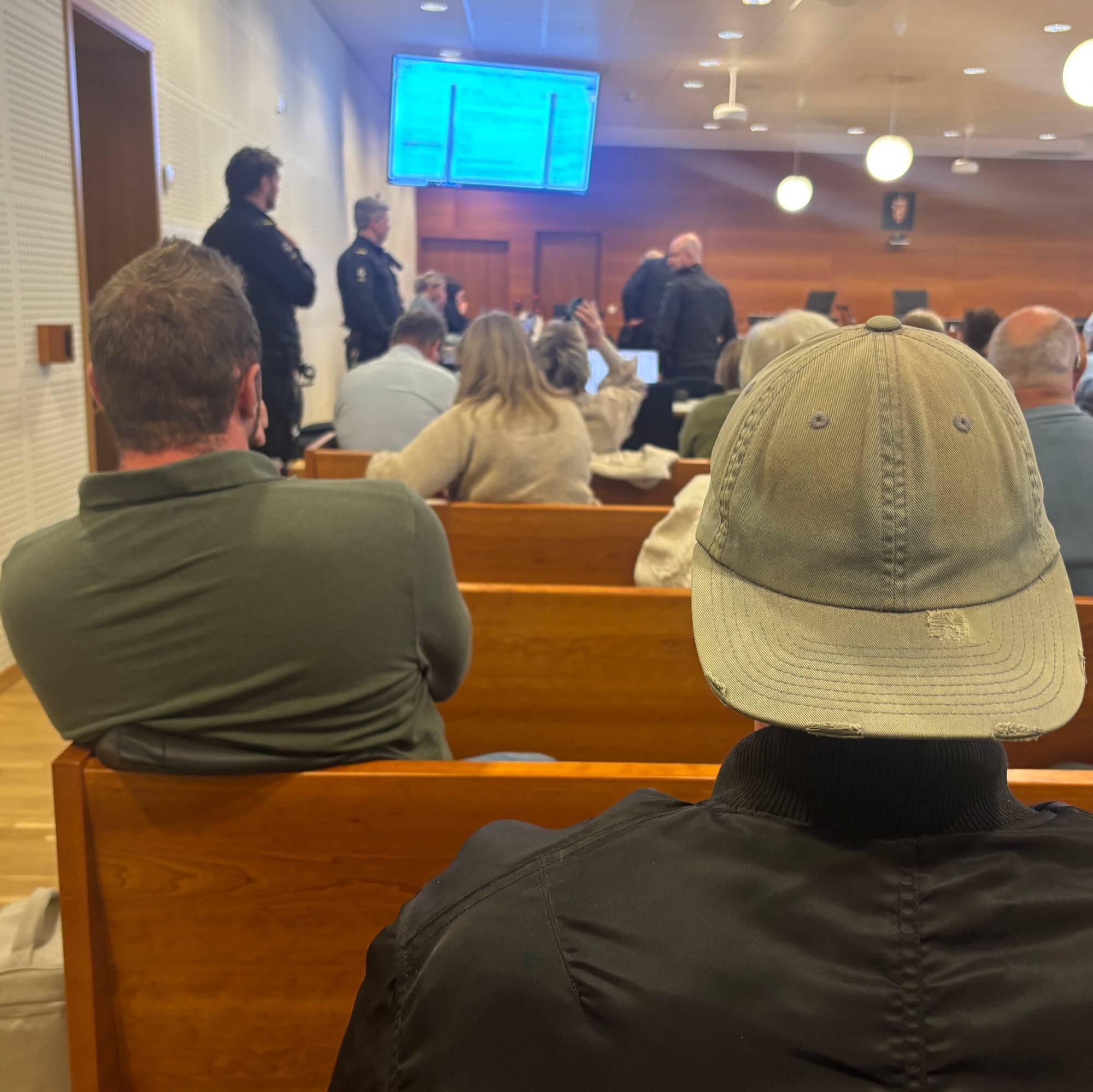 Flere mennesker i en rettssal sett bakfra