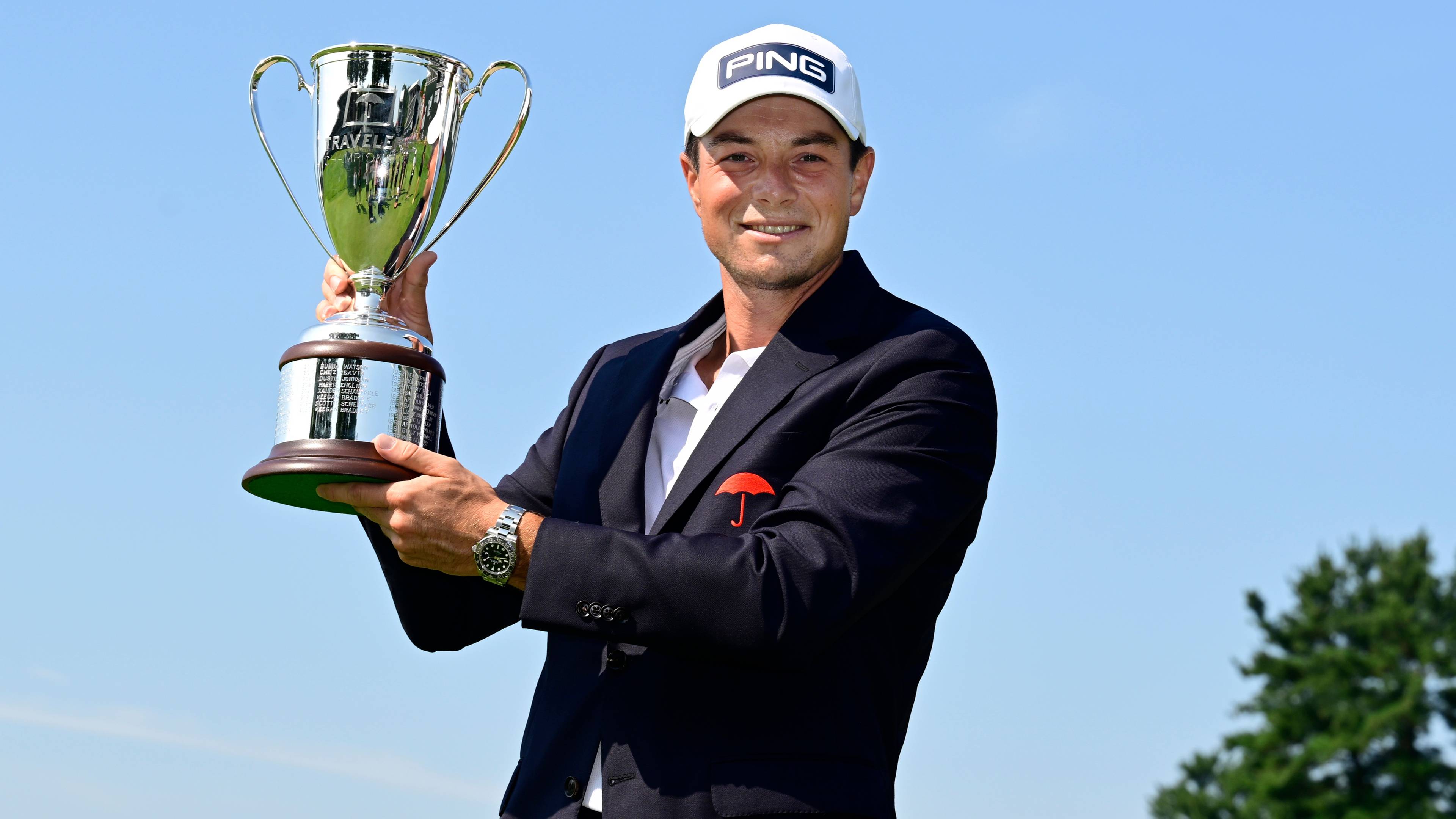 Golfspilleren Viktor Hovland smiler mens han løfter trofeet etter Travelers Championship. (Bildebeskrivelsen er laget av en KI-tjeneste)