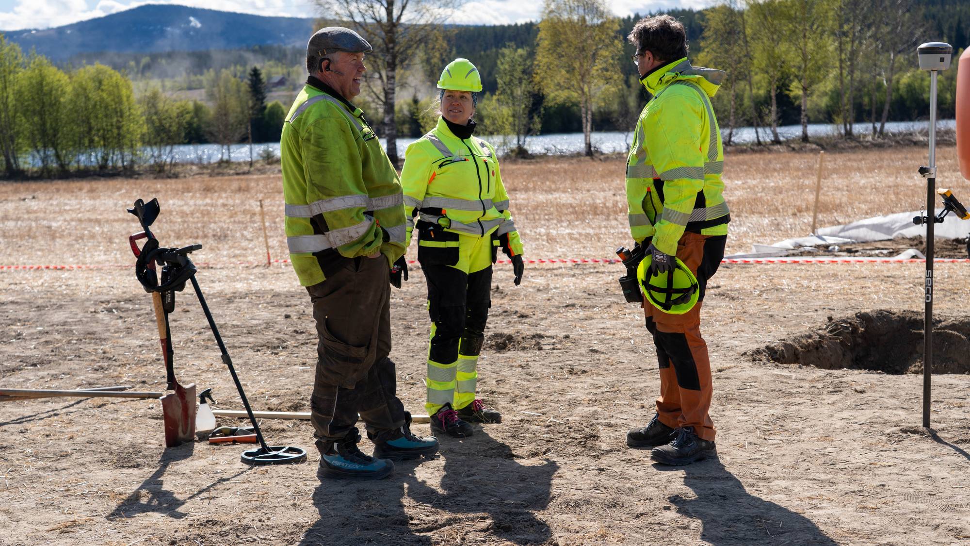 Tre personer står på et jorde ved Glomma 