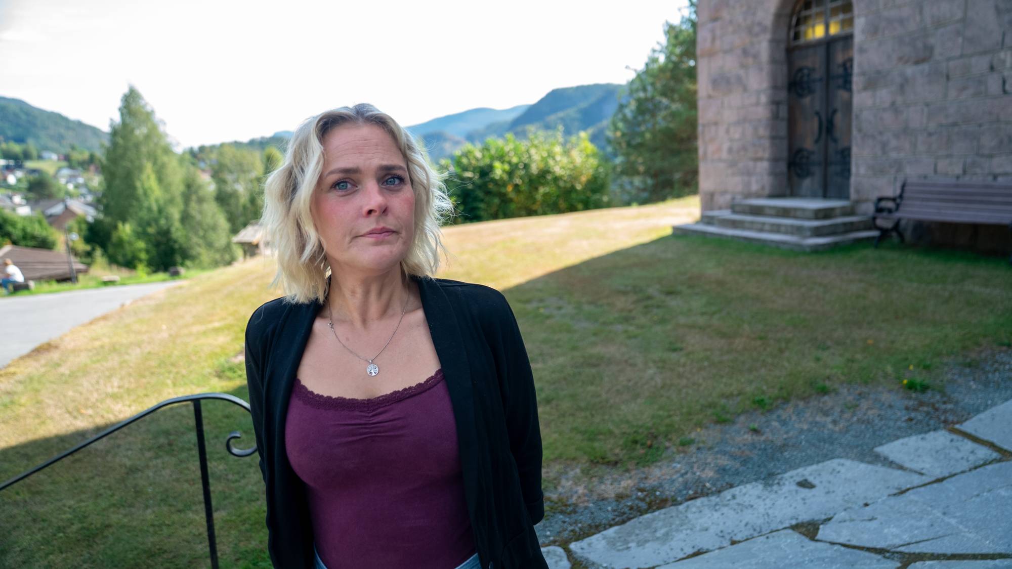 En kvinne står utenfor en kirke og ser mot kameraet.