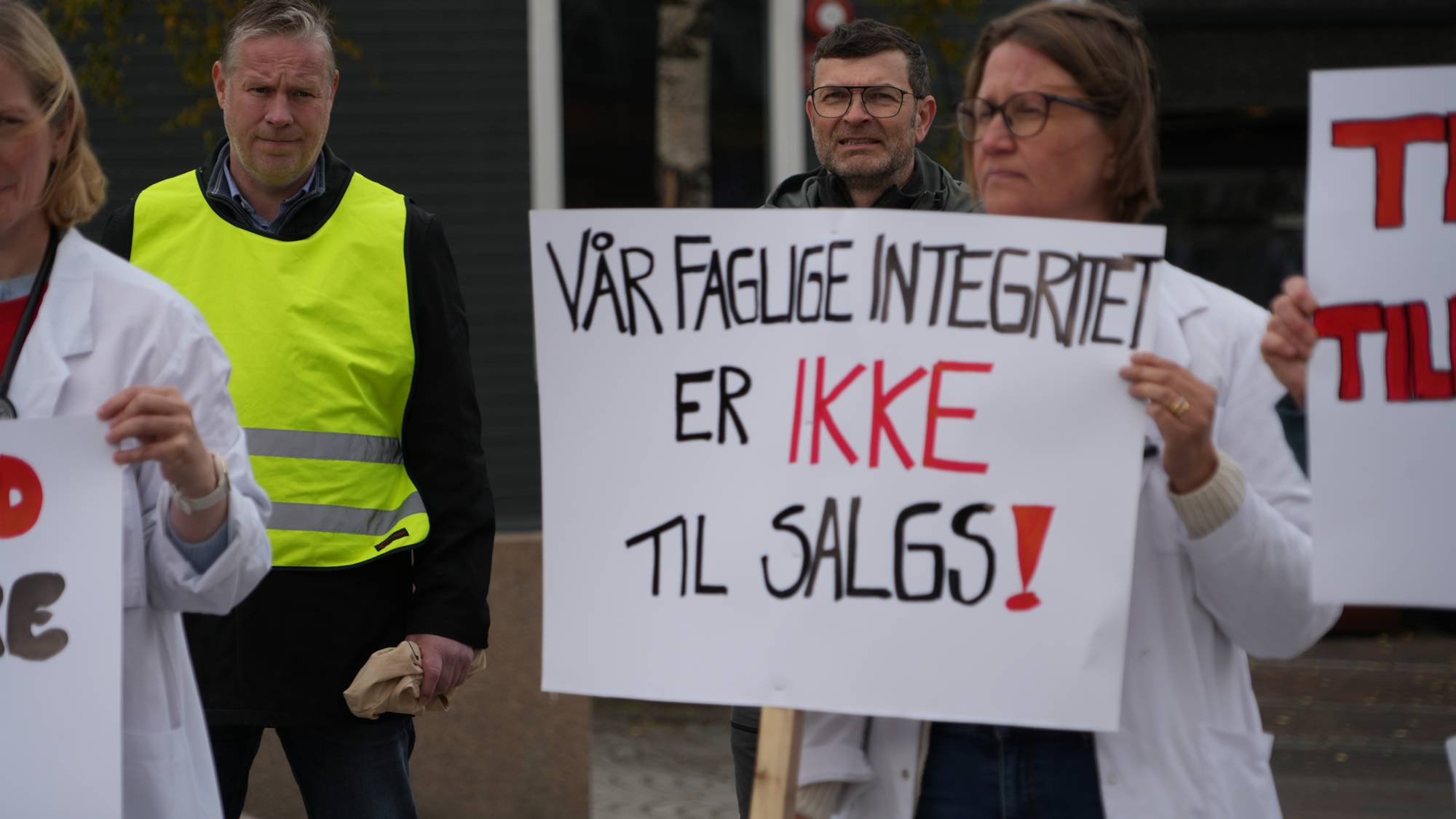 Personer i legefrakker holder plakater med teksten Vår faglige integritet er ikke til salgs. (Bildebeskrivelsen er laget av en KI-tjeneste)