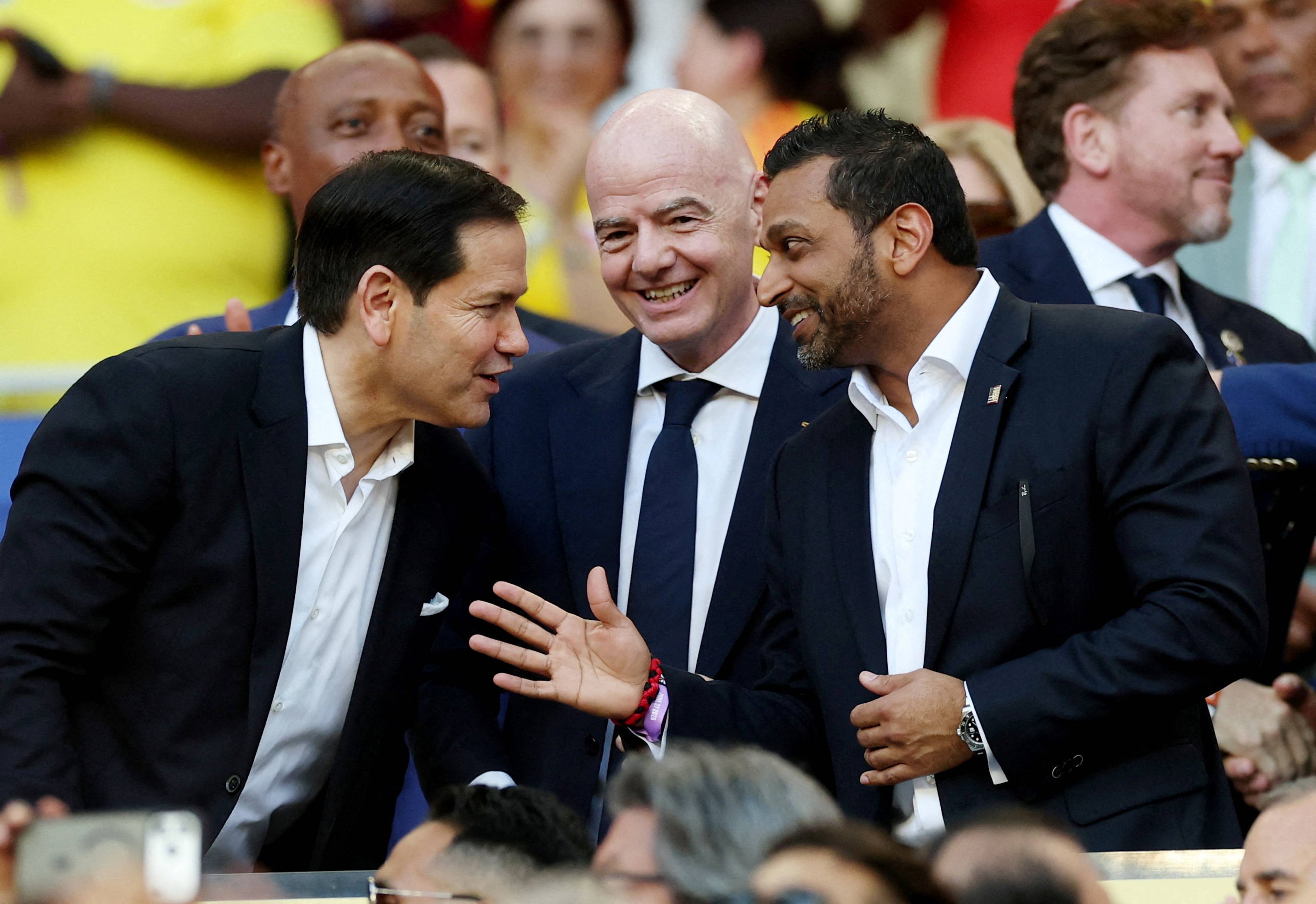 Marco Rubio, Gianni Infantino og ein tredje mann i dress sit saman og samtaler på ein tribune. (Bildebeskrivelsen er laget av ein KI-teneste)