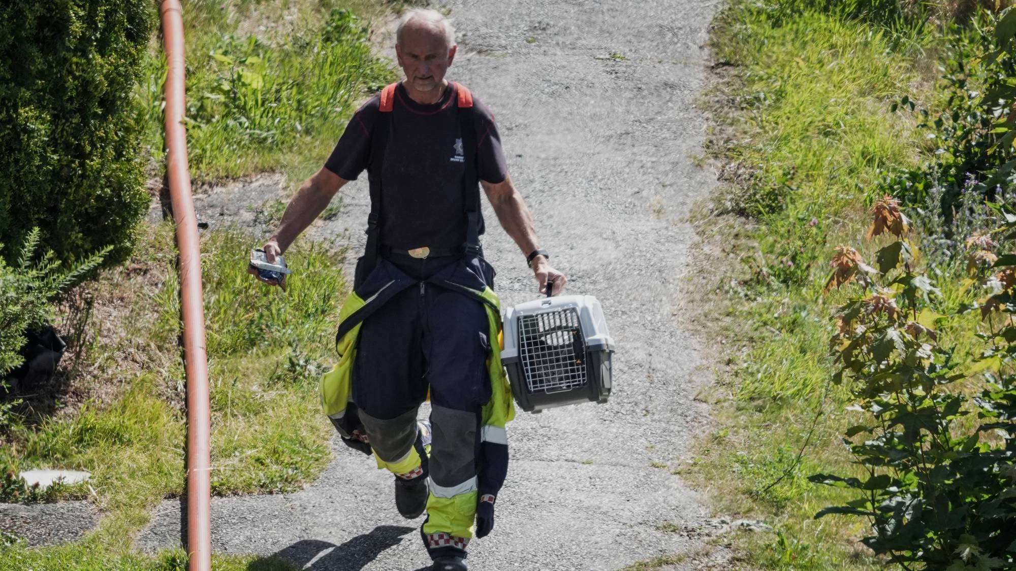 En brannmann går med en katt i bur