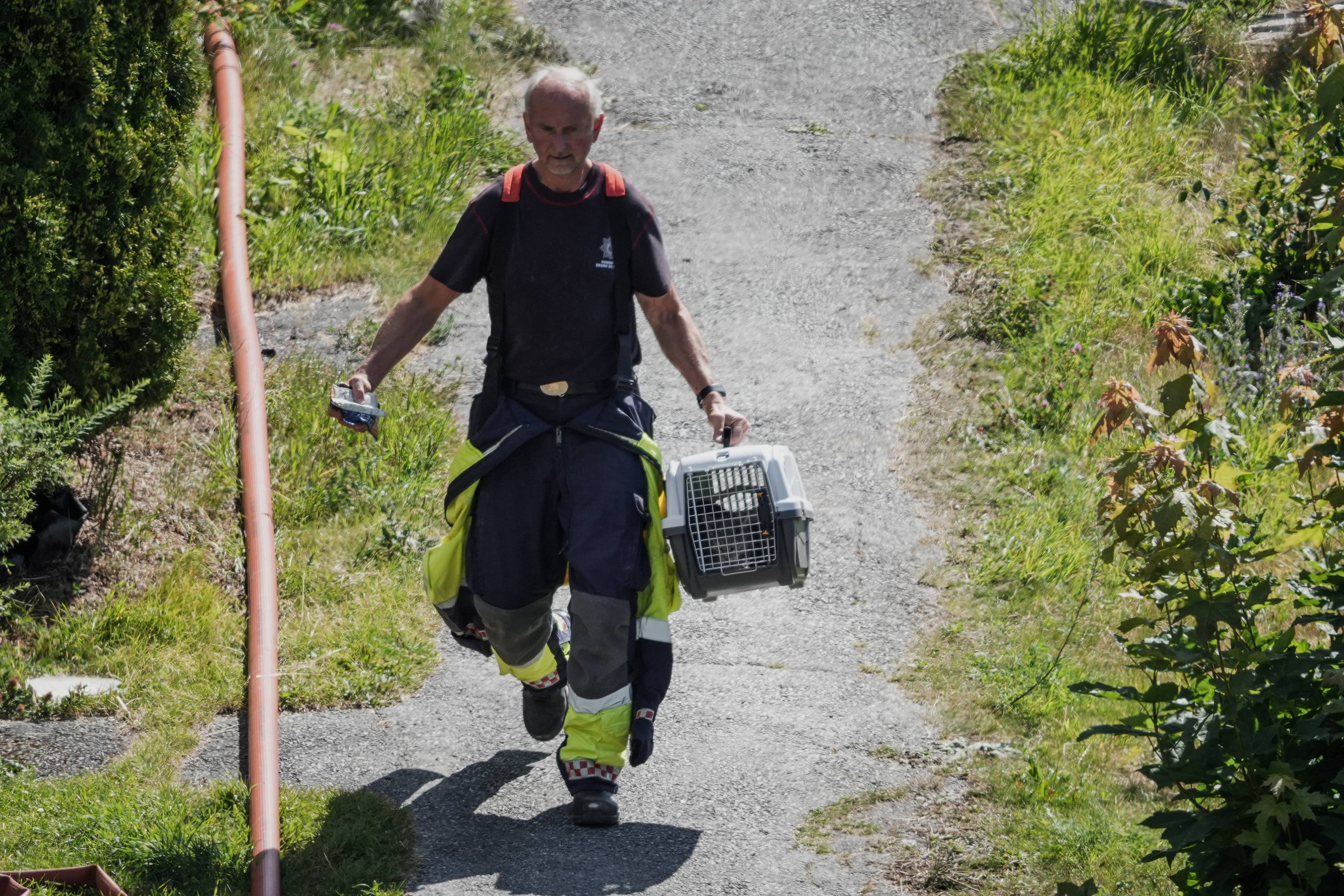 En brannmann går med en katt i bur