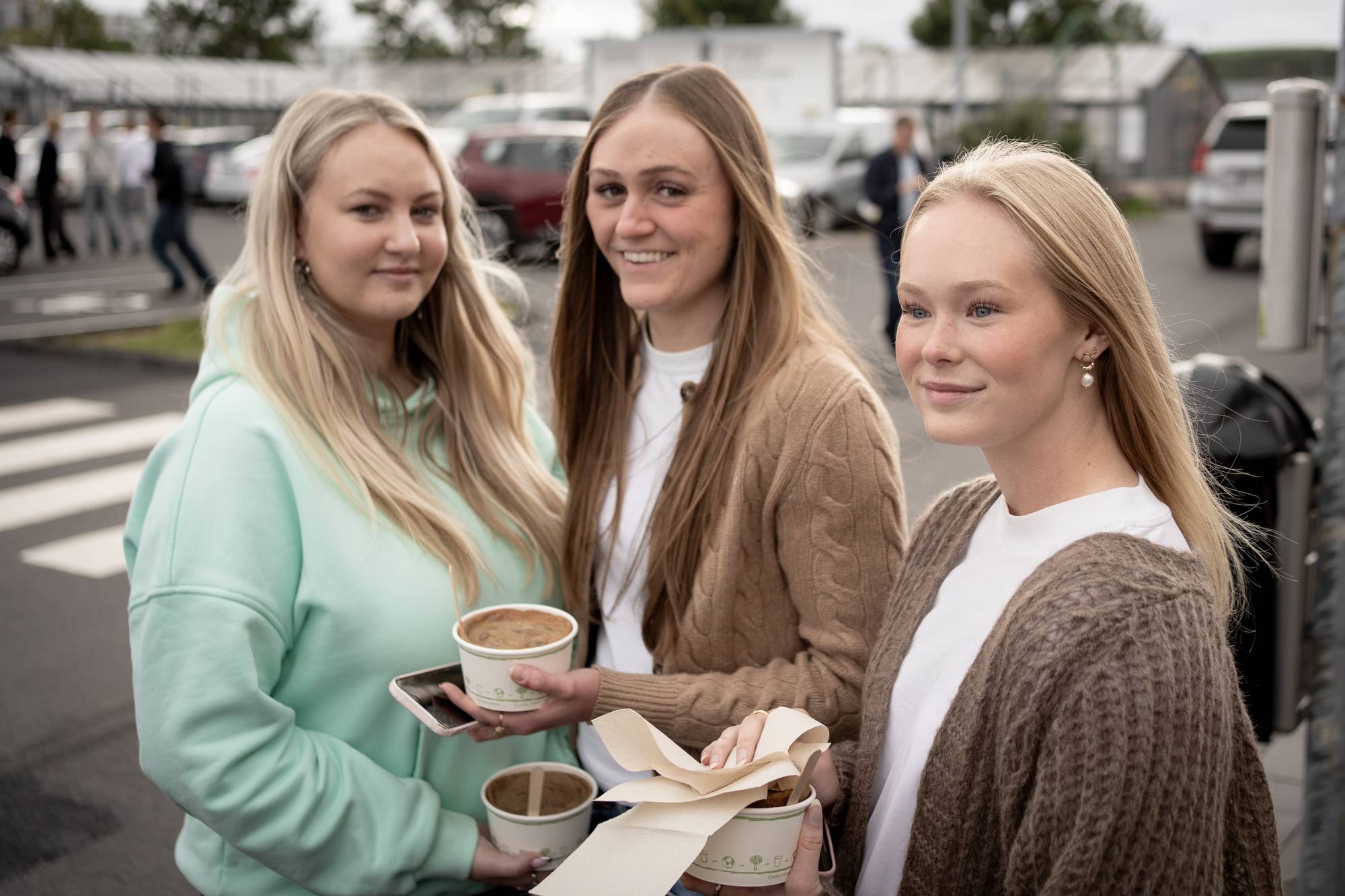 Tre unge kvinner, holder kaffekopp ute på Island