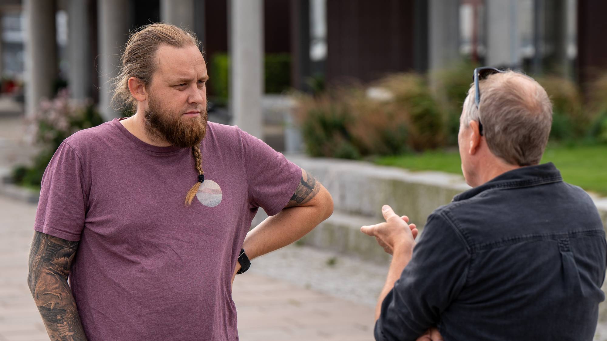 To menn snakker sammen utendørs i et bymiljø. (Bildebeskrivelsen er laget av en KI-tjeneste)
