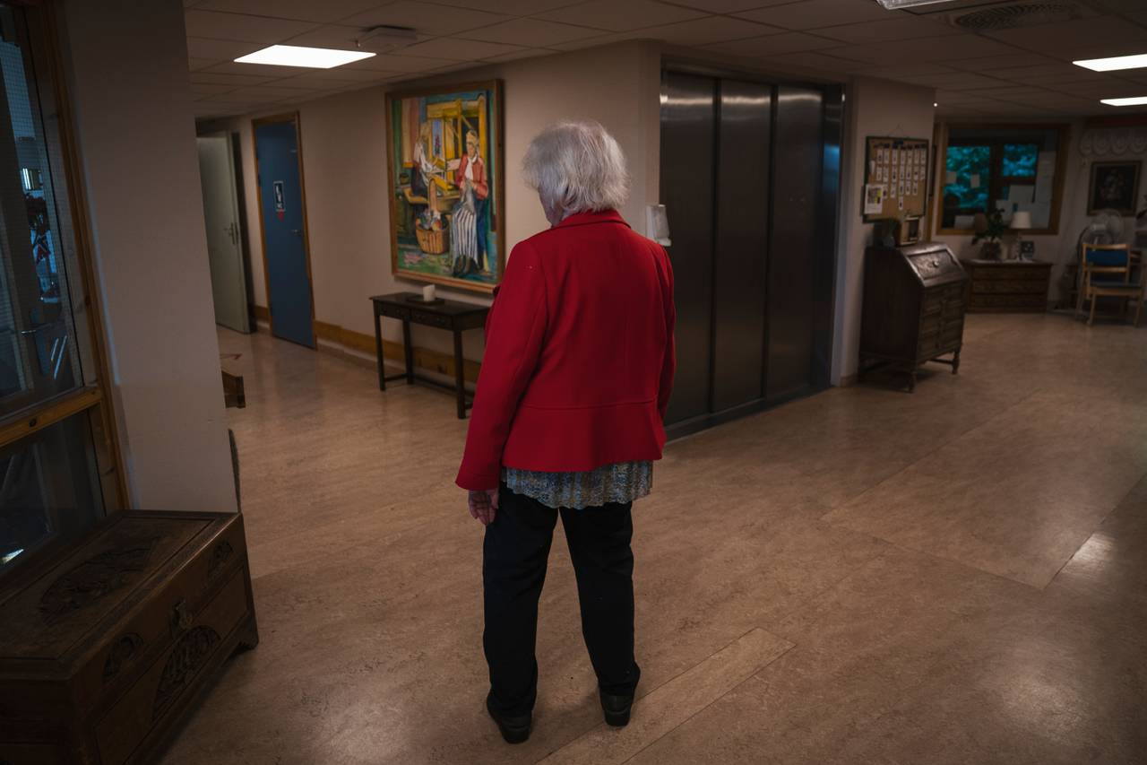 Anne Marie står forvirret i gangen i sin røde jakke og ser mot venstre for å finne ut hvilken vei hun skal gå.