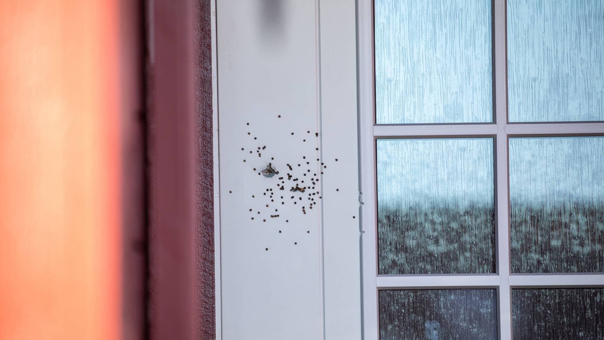 Skuddskader er synlige på en hvit inngangsdør. (Bildebeskrivelsen er laget av en KI-tjeneste)
