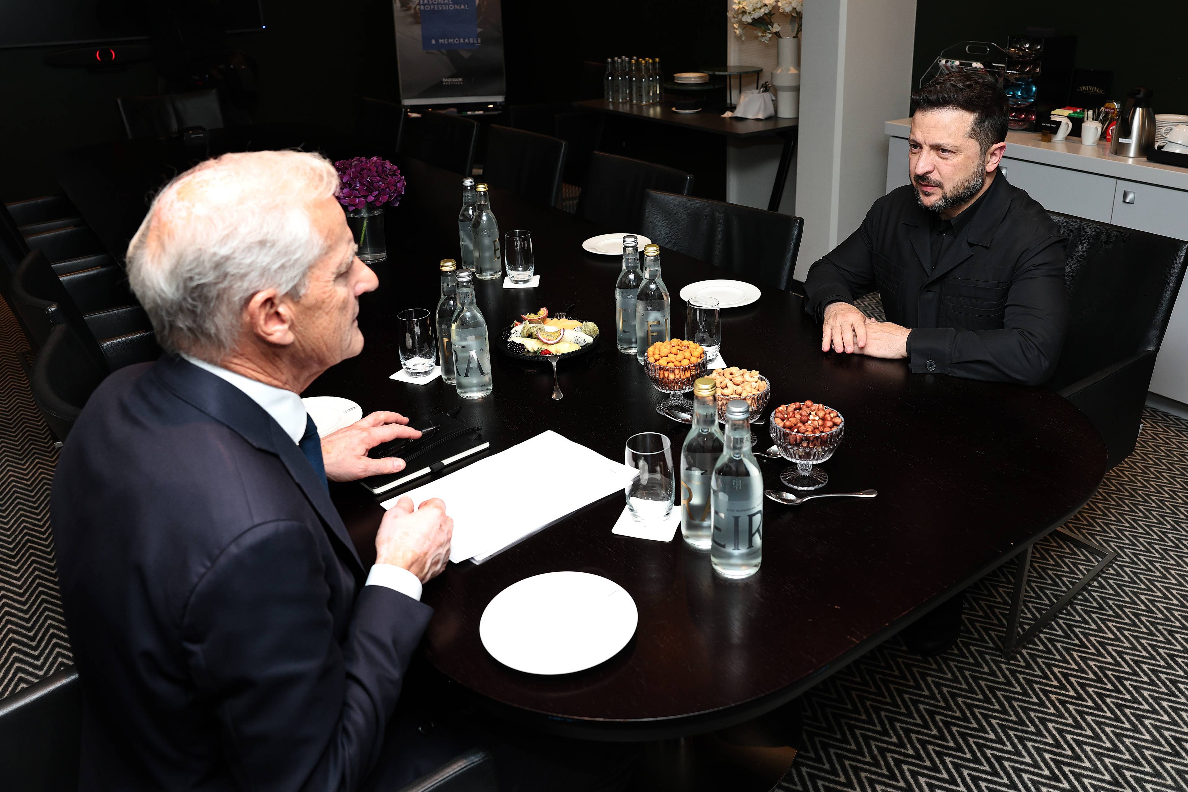 Jonas Gahr Støre og Volodymyr Zelenskyj i møte rundt et møtebord. (Bildebeskrivelsen er laget av en KI-tjeneste)
