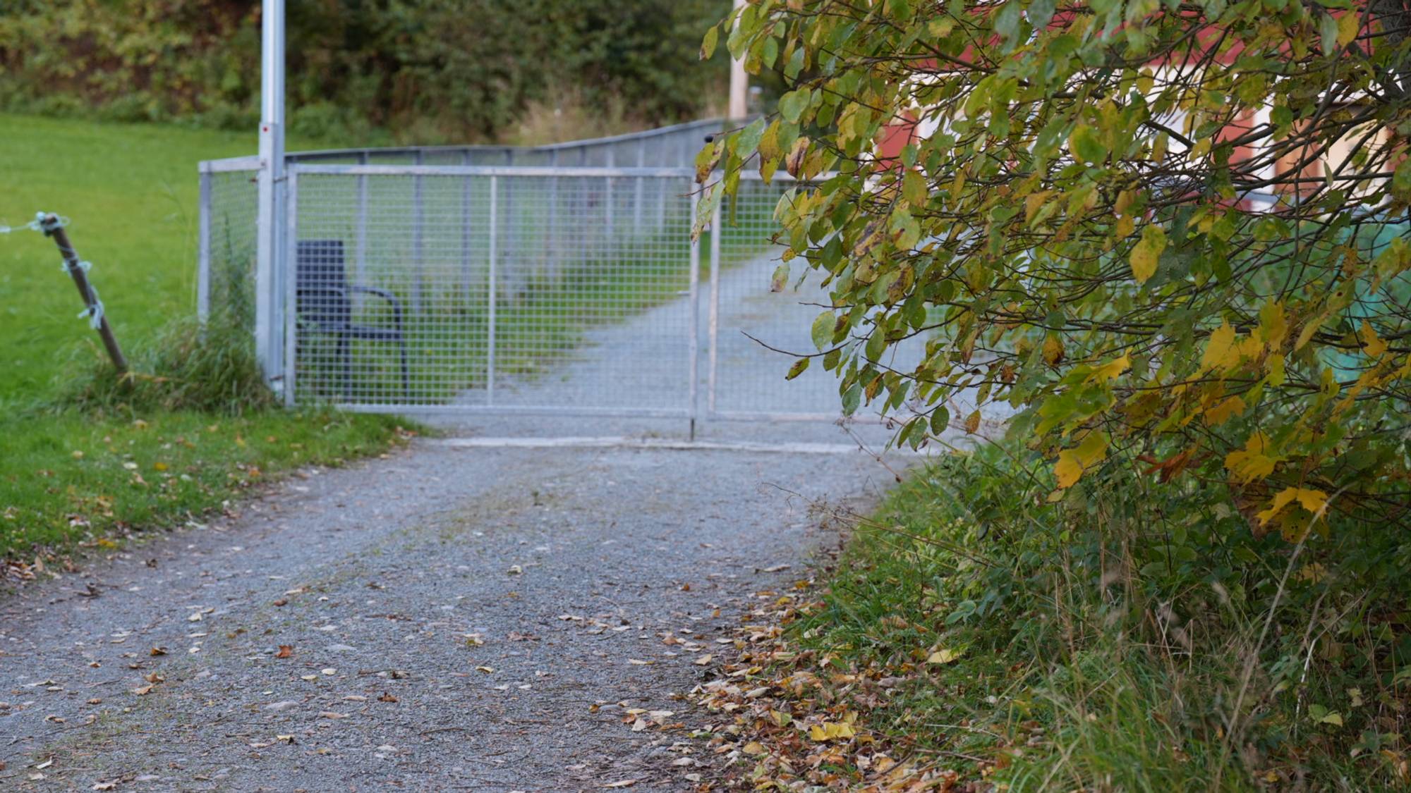 En grussti er stengt med et metallgjerde. Det er grønne omgivelser og trær langs stien. (Bildebeskrivelsen er laget av en KI-tjeneste)