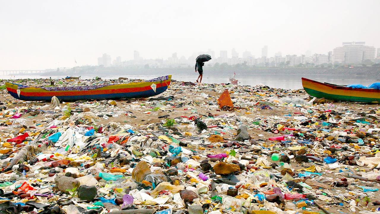 En fisker på stranda i Mumbai i India som er dekket av plast og annet søppel.