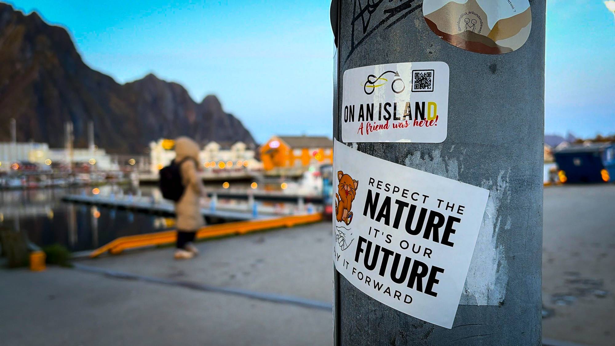 Turister på kaia i Svolvær som tar bilder av fjell og fjord i Lofoten. 