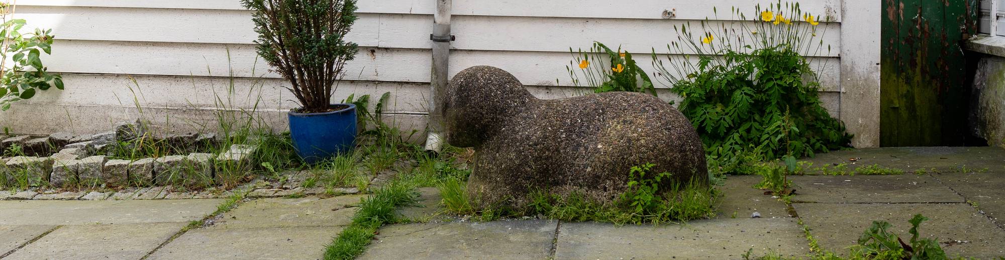 Ein katt av grå stein. Katten har runde former og ein kan ikkje sjå tydelege detaljar som snute og auge så godt
