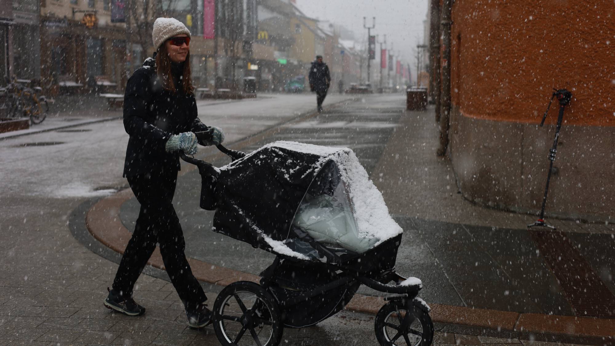 En dame går med barnevogn i tromsø i snø