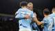 Scott Heppell / Reuters / NTB To spillere fra Manchester City feirer et mål med omfavnelse på banen. Den ene spilleren har nummer 37 og er iført en lyseblå drakt. De øvrige lagkameratene står i nærheten og viser entusiasme. Bakgrunnen viser en mørk stadion med publikum. (Bildebeskrivelsen er laget av en KI-tjeneste)