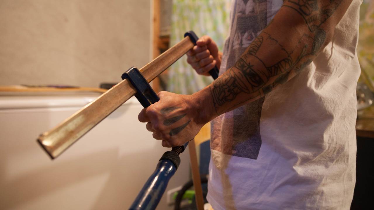 Sterke tatoverte mannearmer holder en tvinge som et gevær