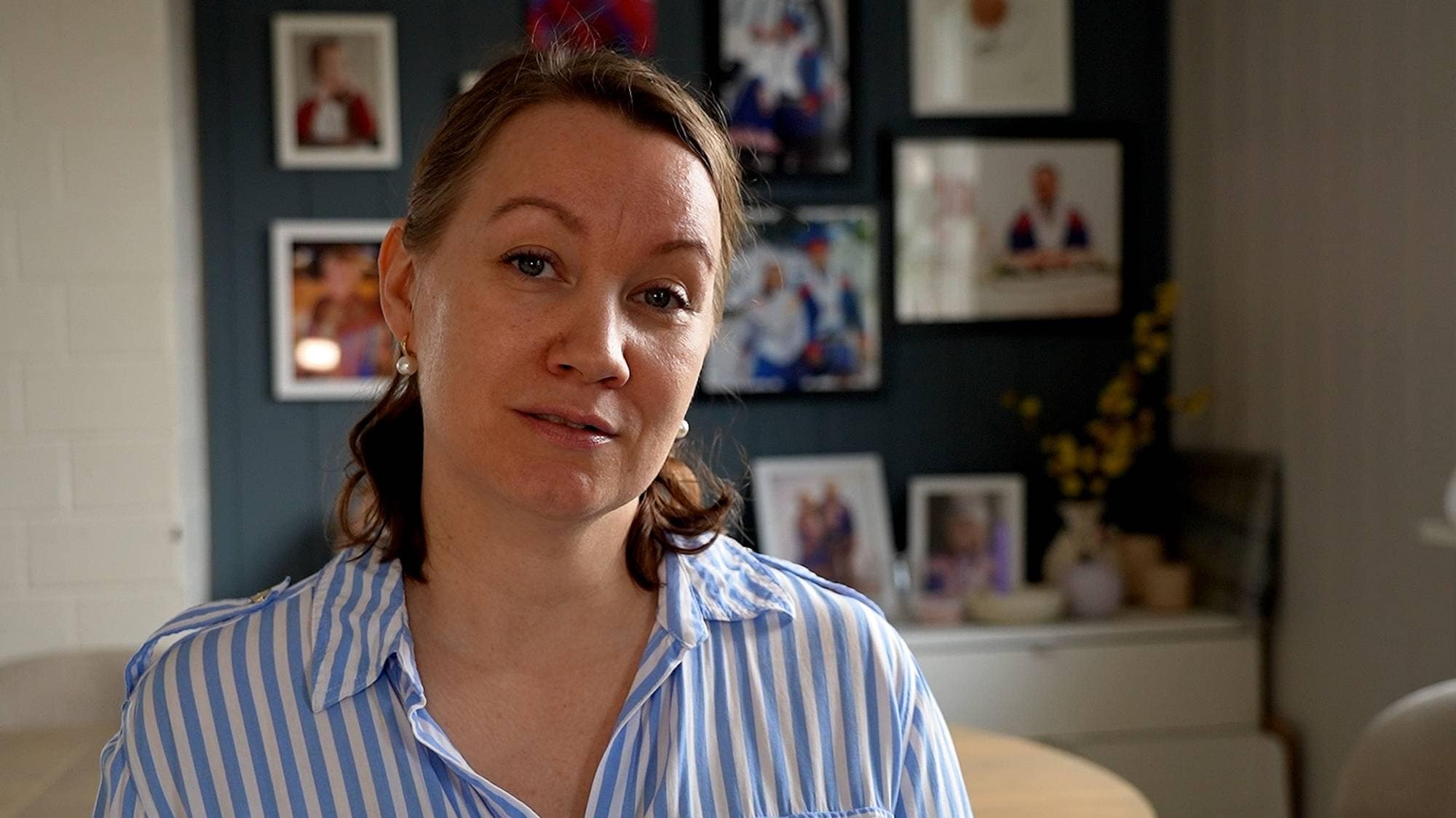 Kvinne står foran en vegg med familiebilder
