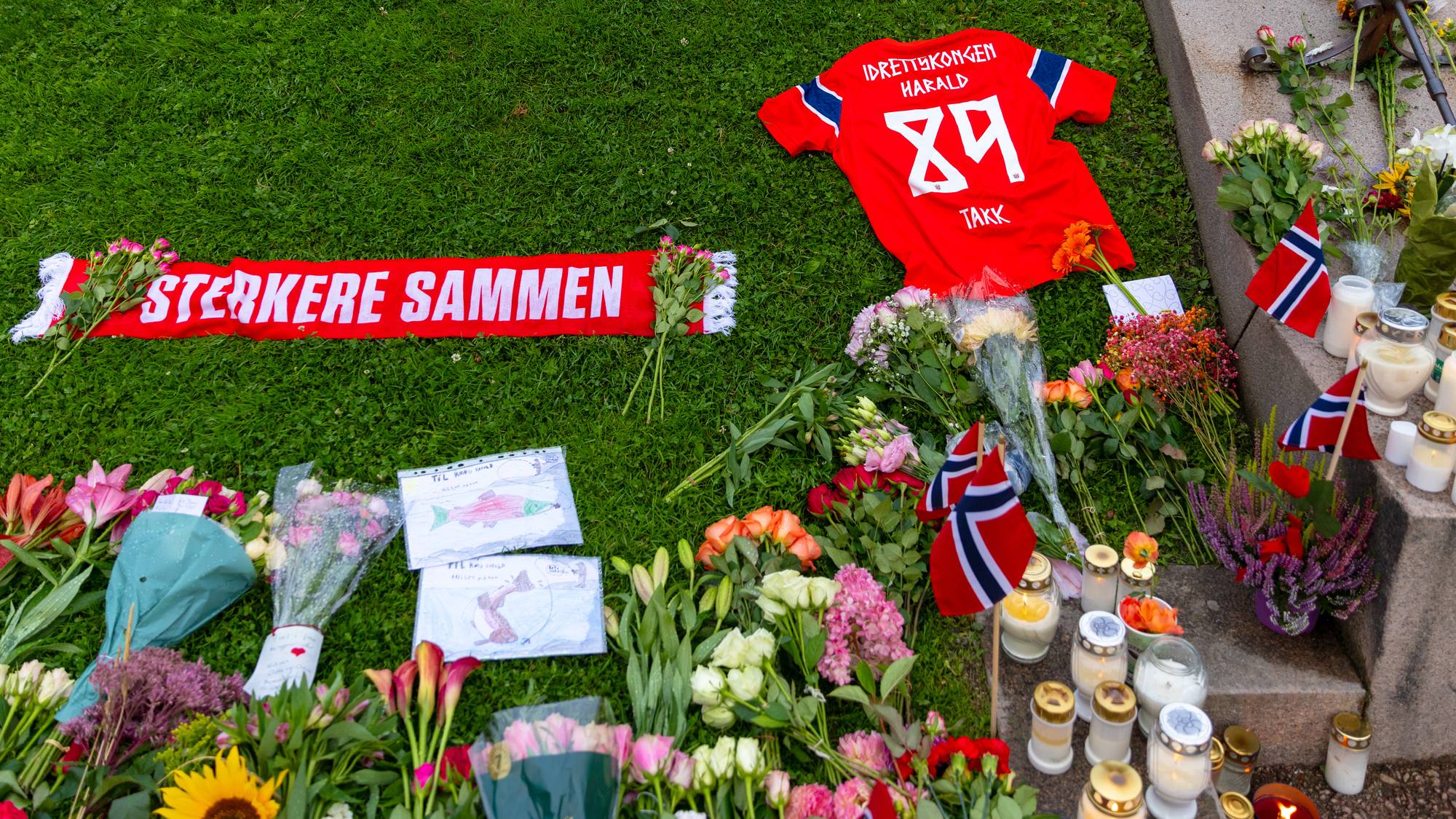 Blomster og tente lys er lagt ned i Slottsparken ved siden av Norges landslagsdrakt med "89" og påskriften "Idrettskongen Harald på ryggen