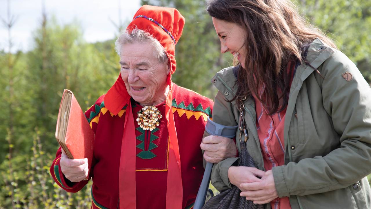 Astrid Jonskareng ser på en rød bok og ler