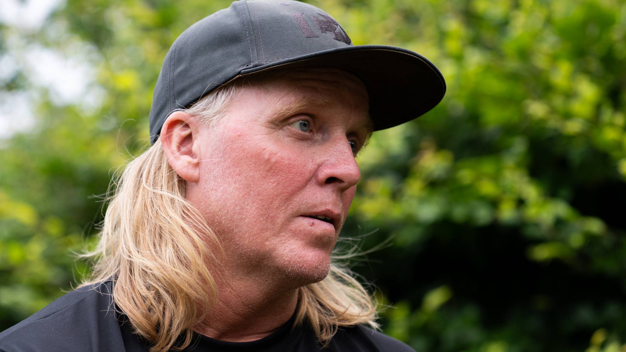 Vegard Høidalen som snakker i et intervju, kledd i svart skjorte og caps