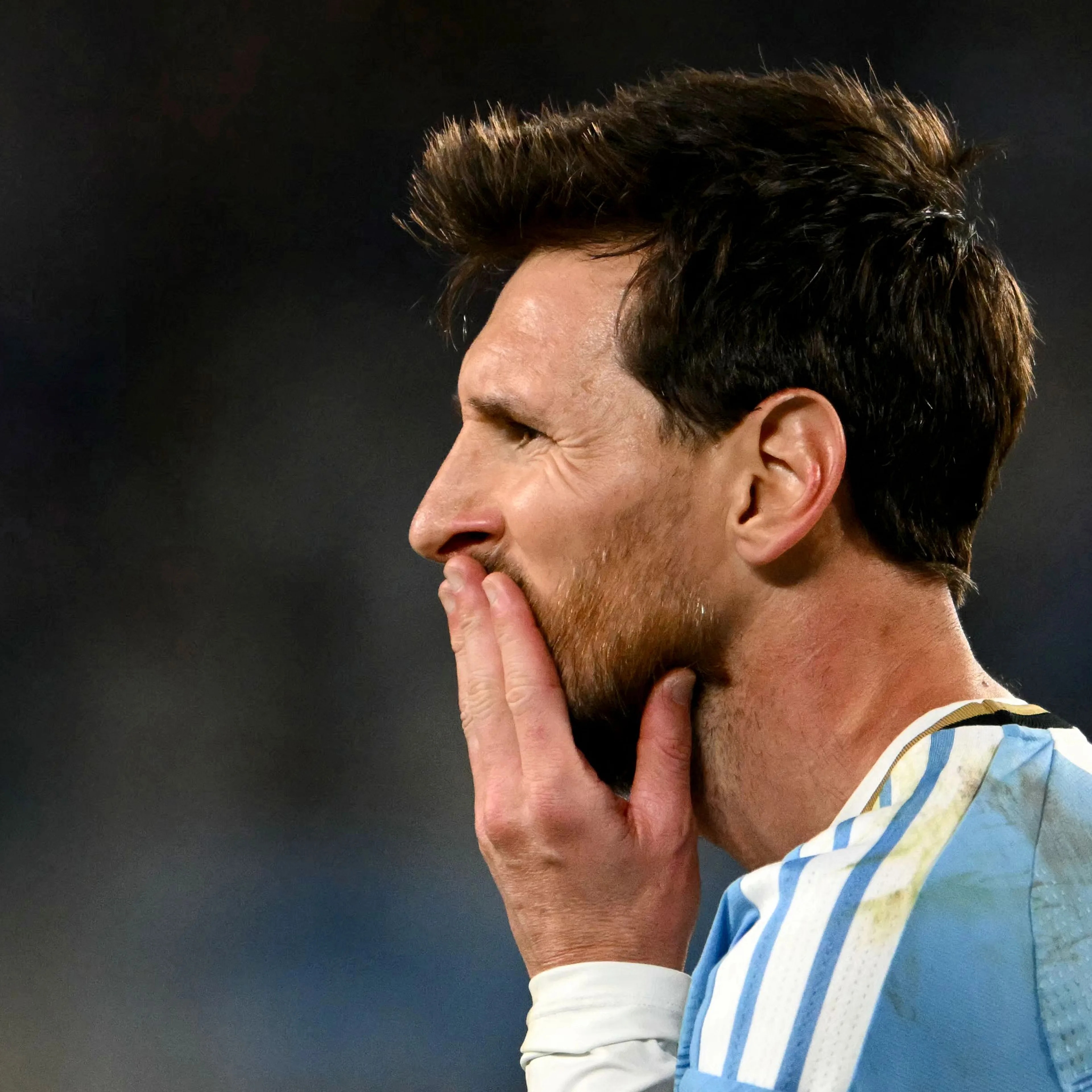 Lionel Messi i profil med hånden foran munnen, iført landslagsdrakt for Argentina. (Bildebeskrivelsen er laget av en KI-tjeneste)