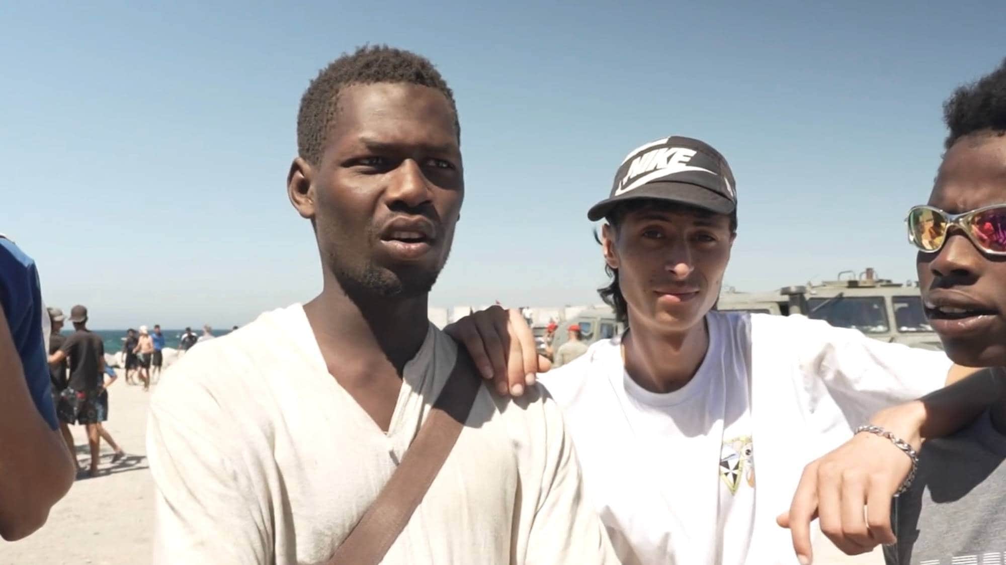 Tre unge menn står ved sida av kvarandre. To av dei ser ut som dei er frå Afrika sør for Sahara, ein ser nordafrikansk ut.