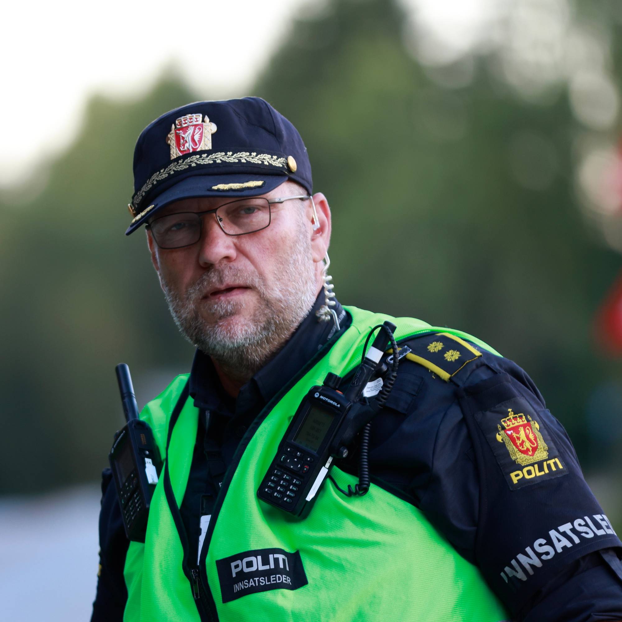 Politimann med grønn refleksvest, politicaps og briller