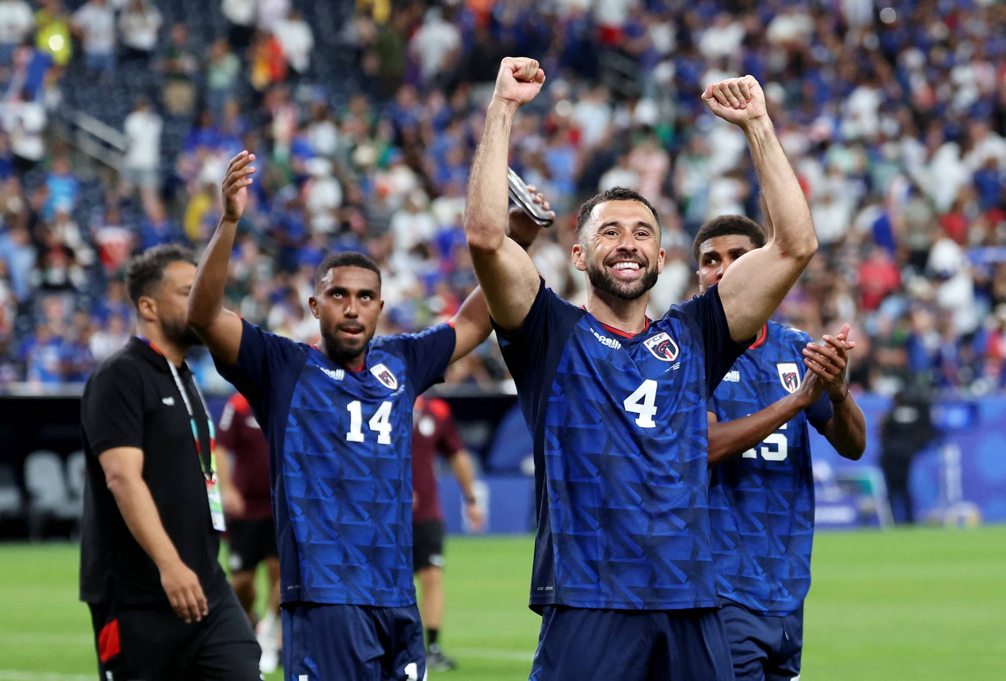 Fotballspillere i blå drakter jubler med armene i været på en stadion. 