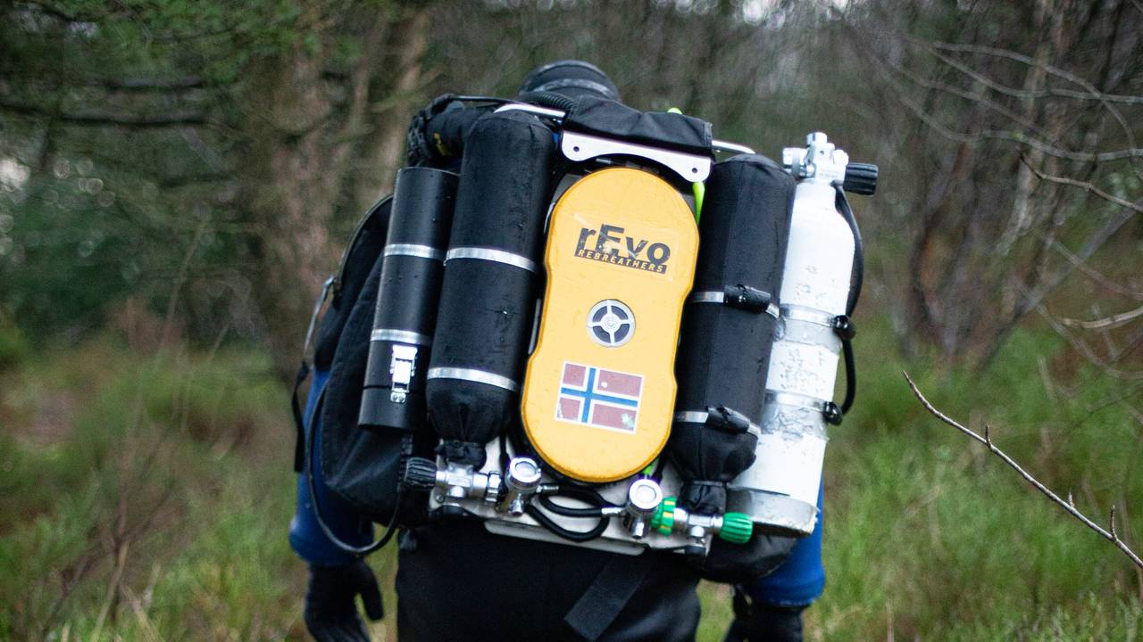 Espen Rekdal går gjennom skogen ikledd dykkerutstyr og med oksygenflasker på ryggen