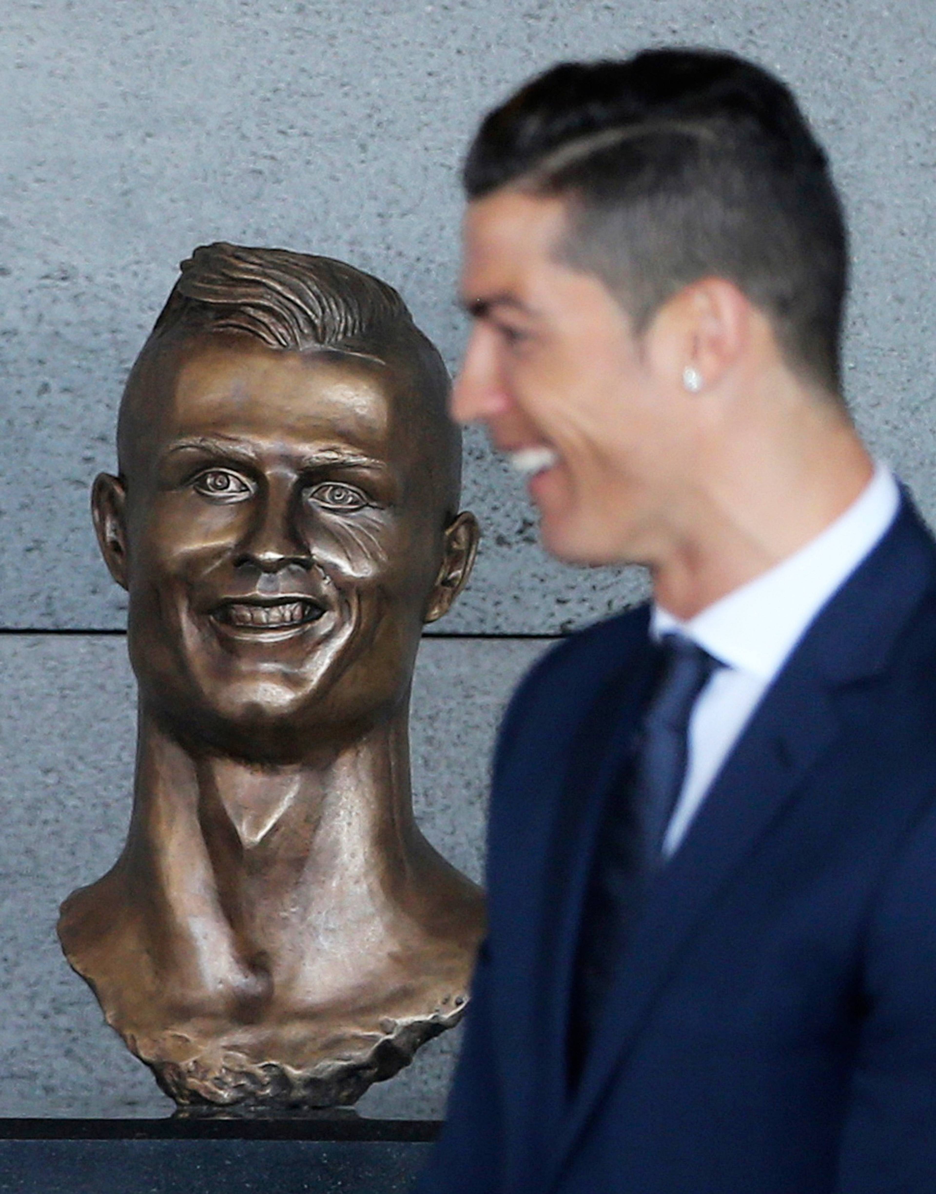 Cristiano Ronaldo står ved siden av en byste av seg selv. (Bildebeskrivelsen er laget av en KI-tjeneste)