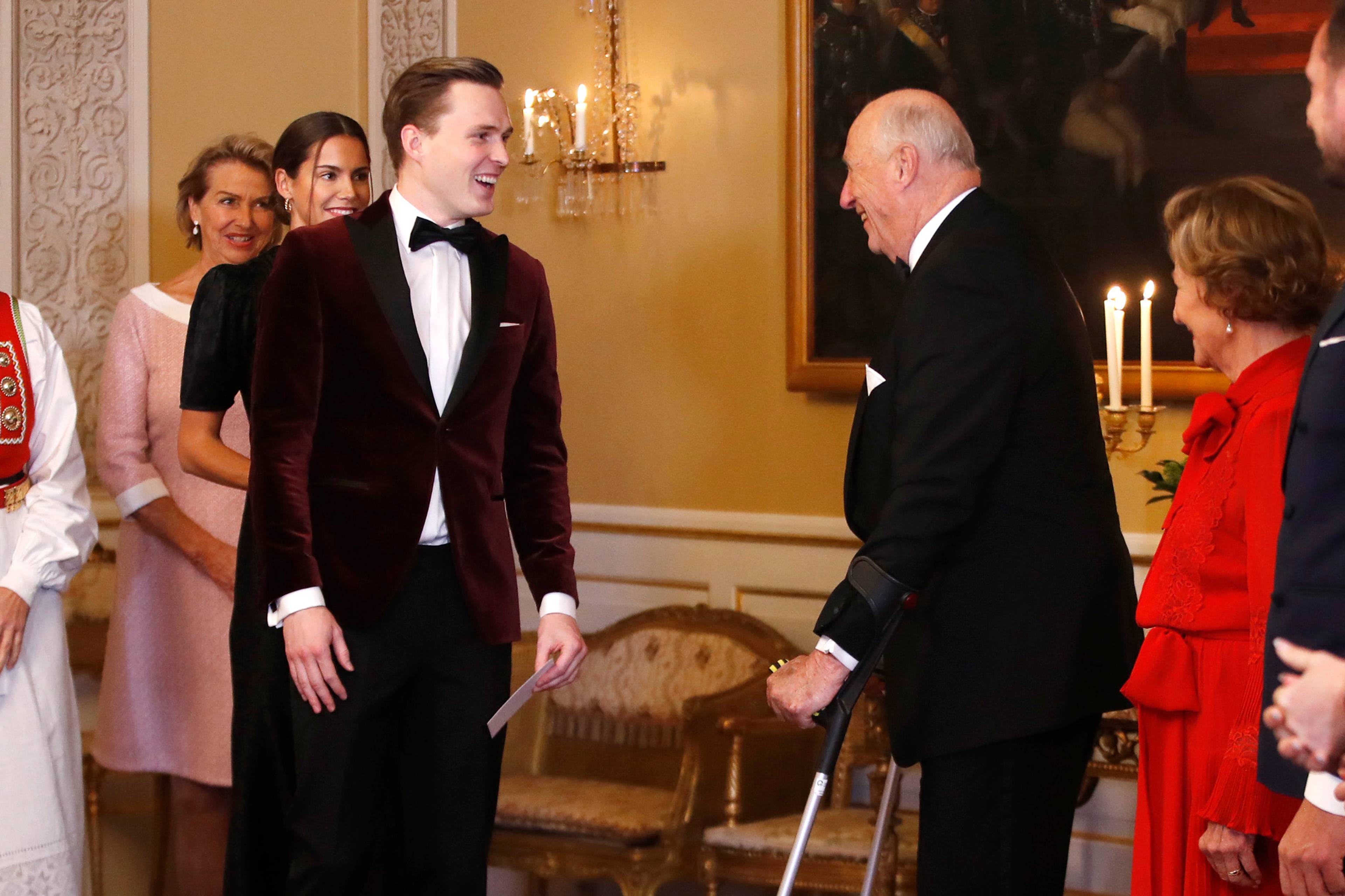 Kong Harald og dronning Sonja tar imot gjester i et selskap på Det kongelige slott. (Bildebeskrivelsen er laget av en KI-tjeneste)