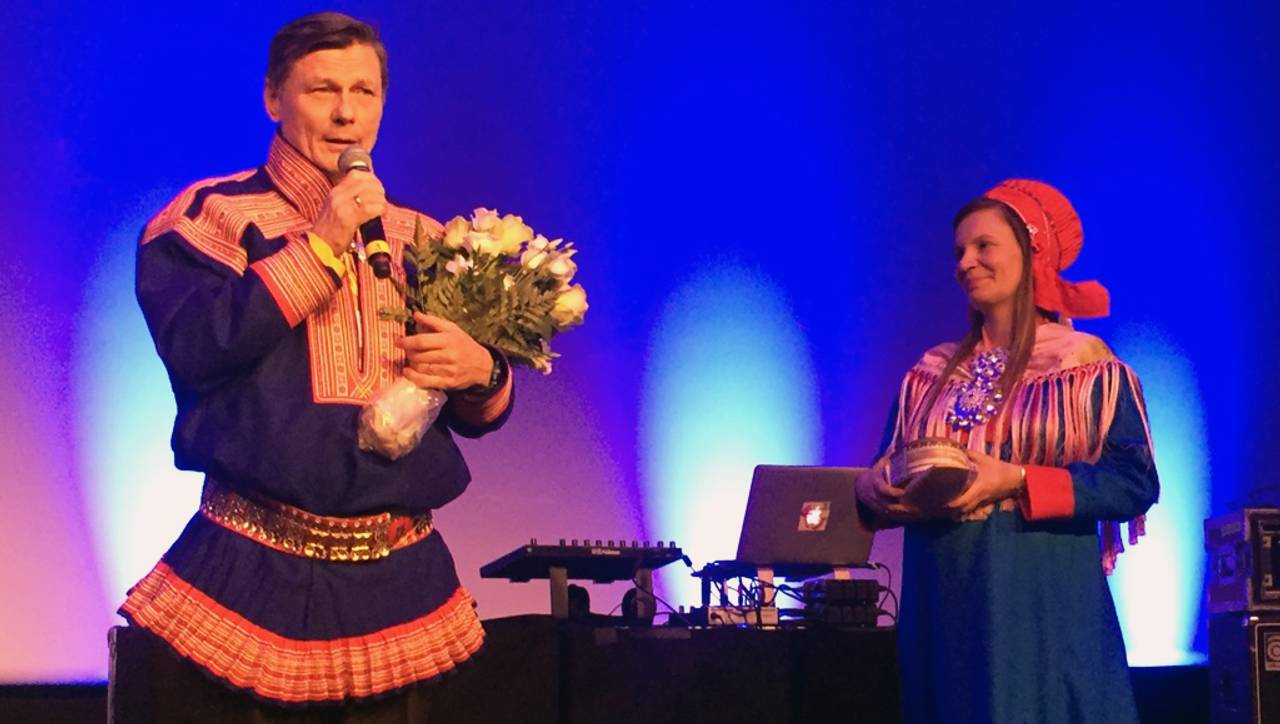 Ole Henrik Magga med mikrofon og blomster sammen med Áile Javo