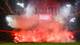 OLAF KRAAK / AFP / NTB Et stadion er fylt med røyk og lys fra bengalluer under en fotballkamp. Fansen er synlige i bakgrunnen, omgitt av røde flammer. En stor skjerm advarer om at fyrverkeri er forbudt. Omgivelsene gir en intens atmosfære til arrangementet.